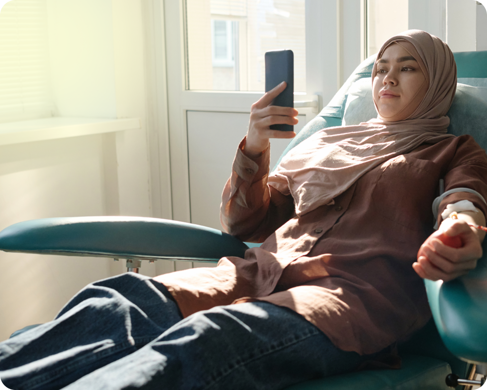 Woman getting her blood taken while scrolling on her phone 