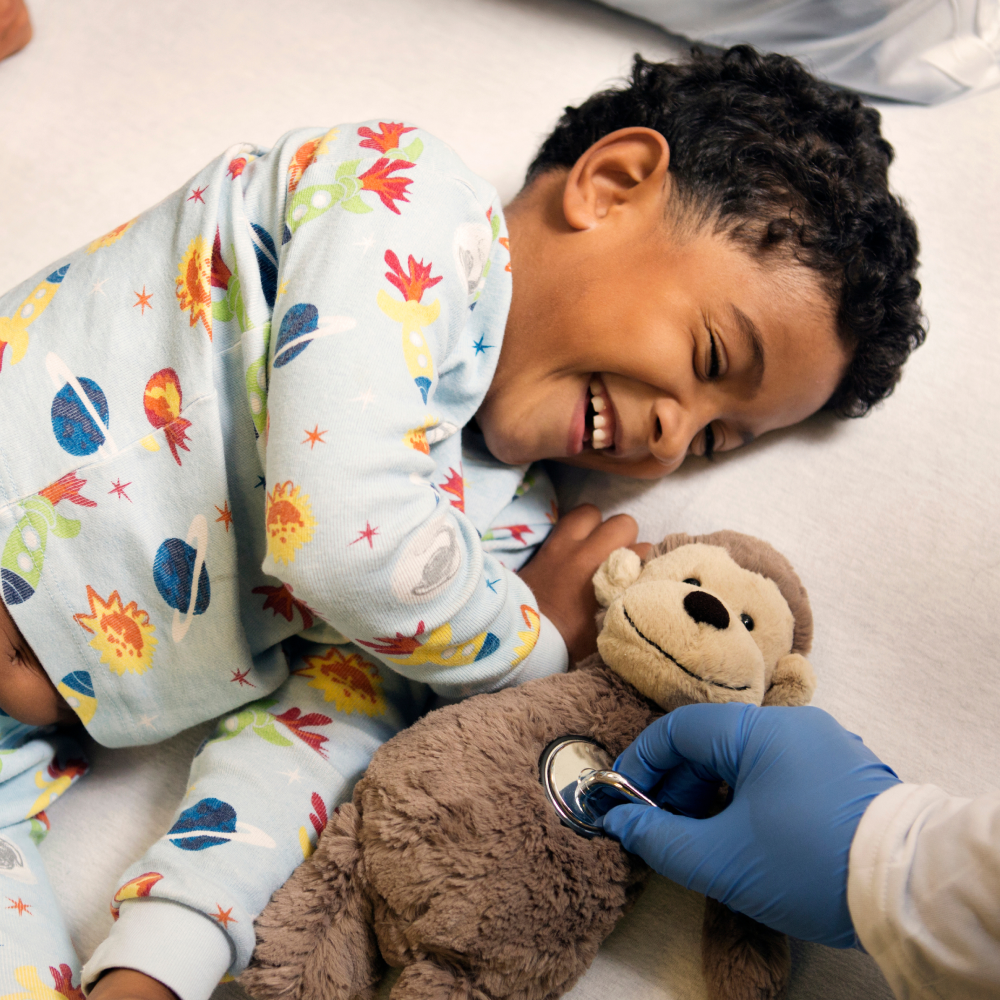 Child laughing at doctor's holding a teddy bear