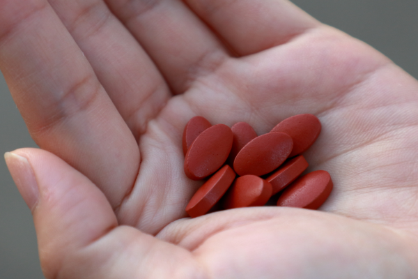 iron supplements with some pills spilling in a person's palm
