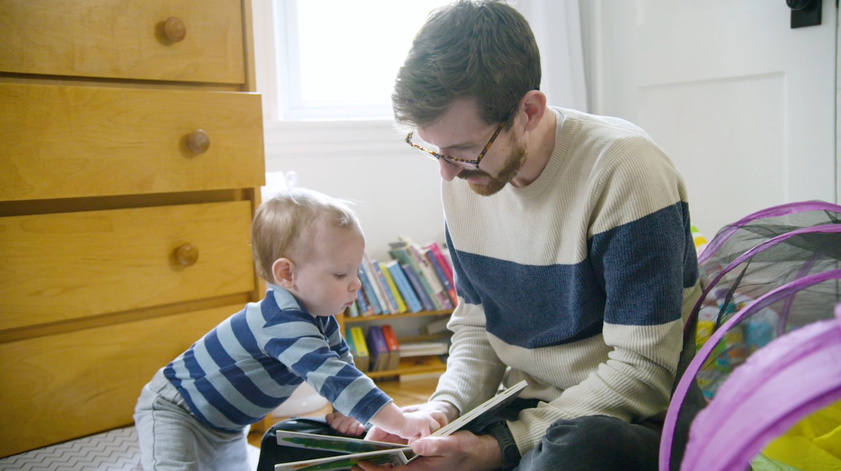 Keegan at home reading a book with his young son