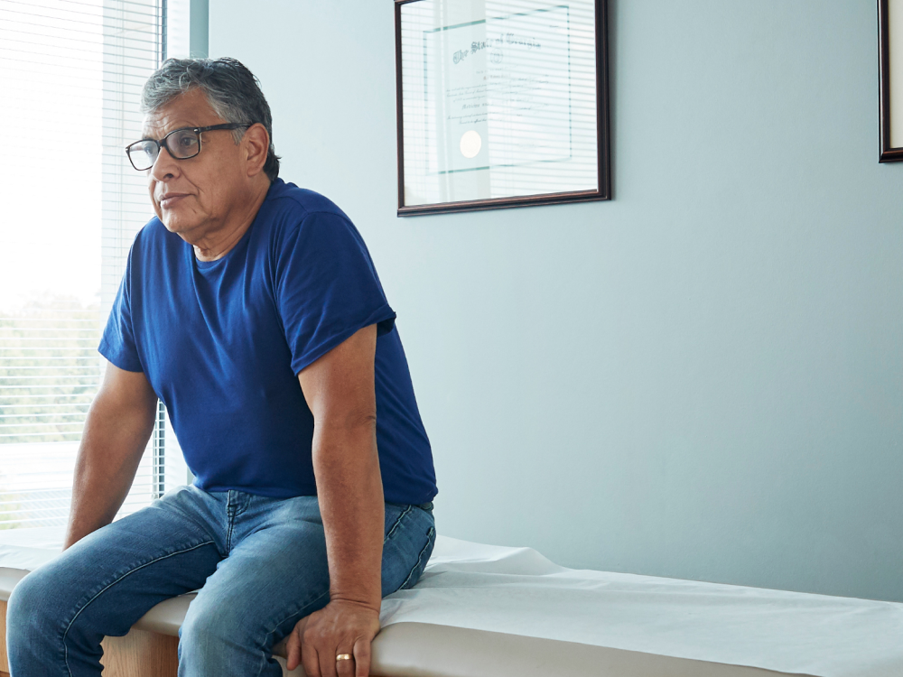 older male sitting on a exam bench at a provider's office