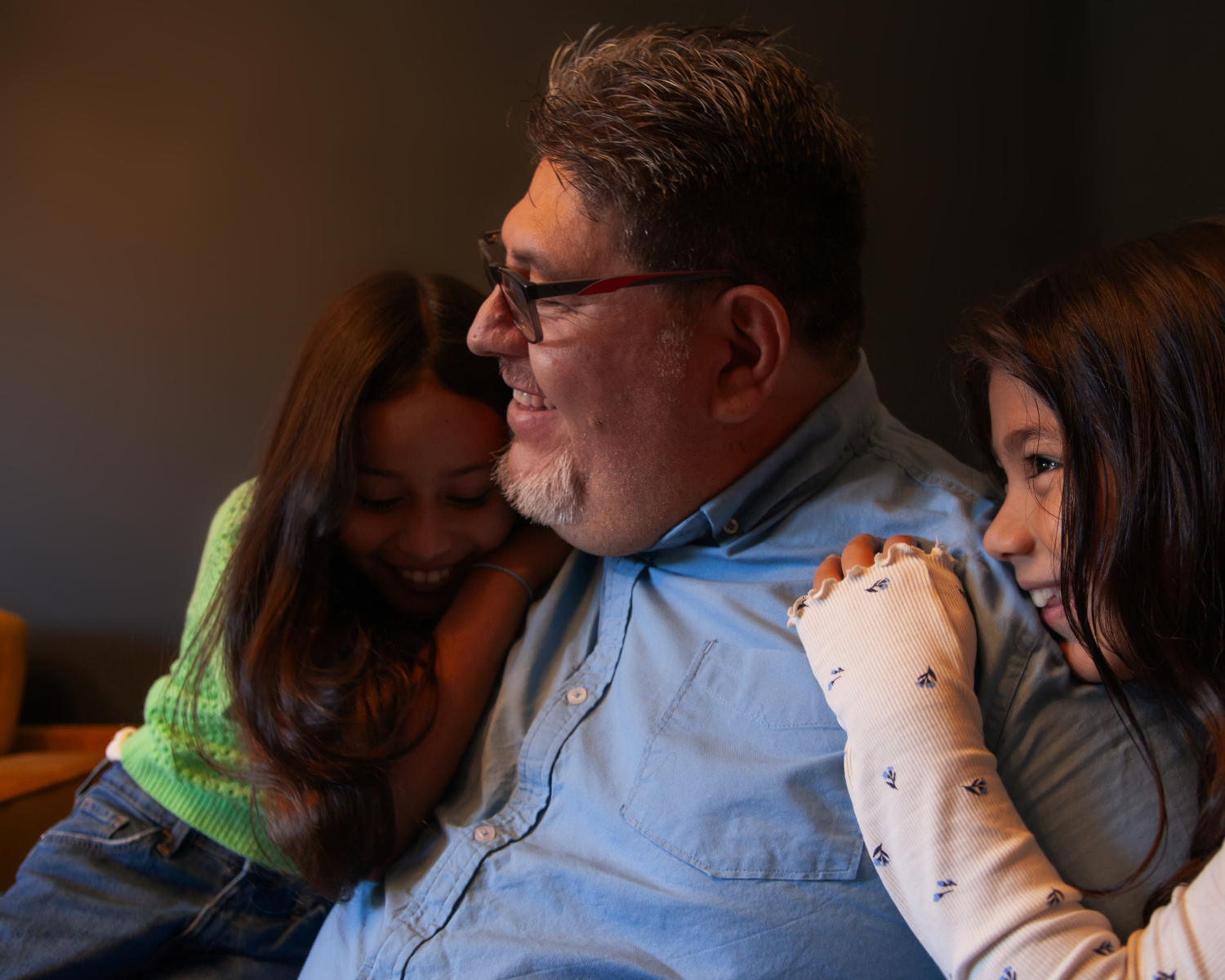 photograph of a man hugging his daughters 