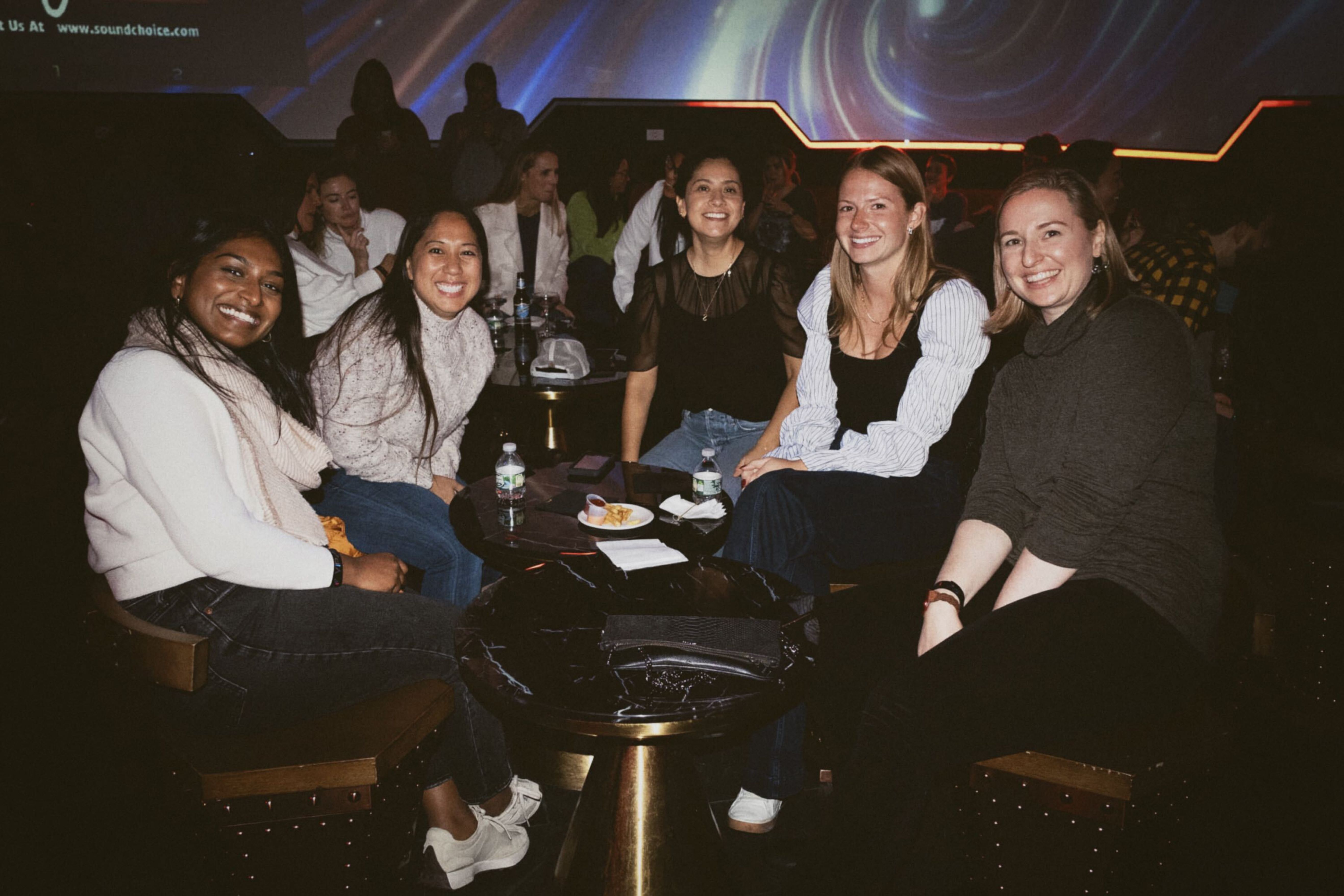 group of firefly employees smiling around a table at a post work event 