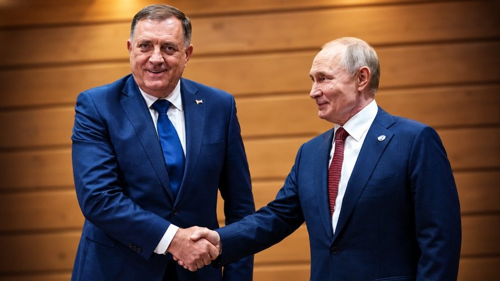 Milorad Dodik i Vladimir Putin u tamnoplavim odijelima rukuju se ispred drvenog zida