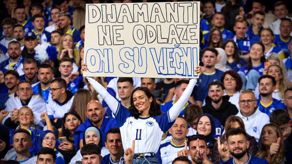 Navijačica u bijelo-plavom dresu broj 11 diže transparent „Dijamanti ne odlaze, oni su vječni“ na punoj tribini.
