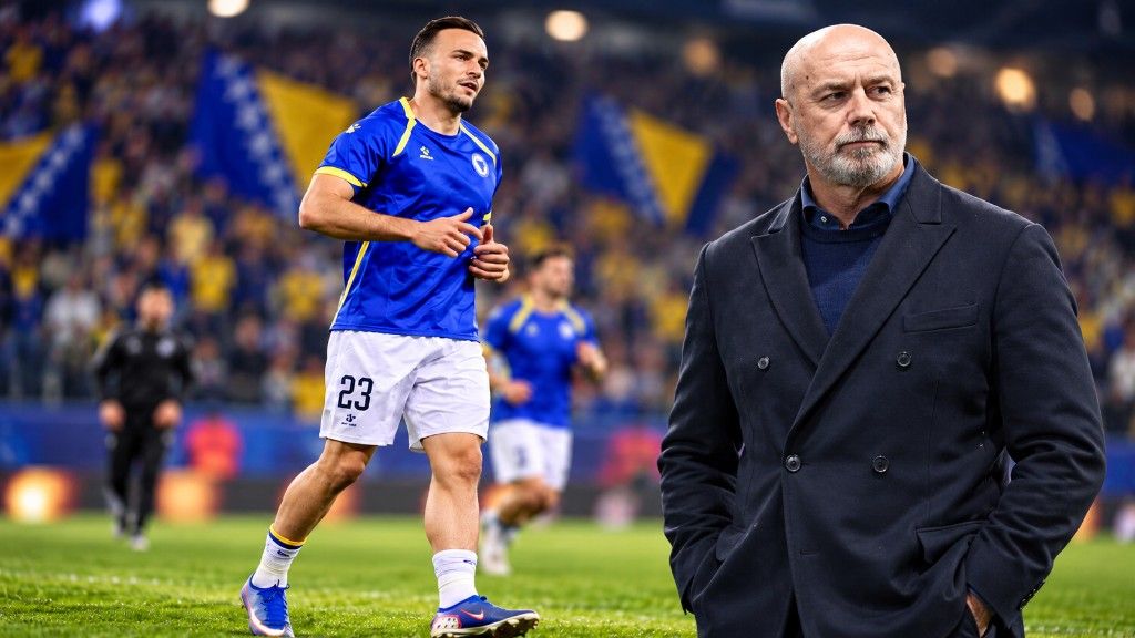 Napadač Zmajeva u plavom dresu s brojem 23 i ćelav muškarac u tamnom odijelu na stadionu punom zastava Bosne i Hercegovine