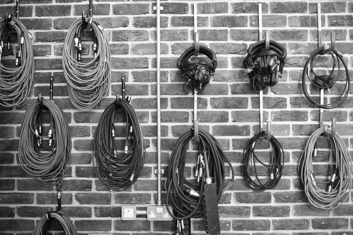 Microphone cables and headphones hanging on a brick wall