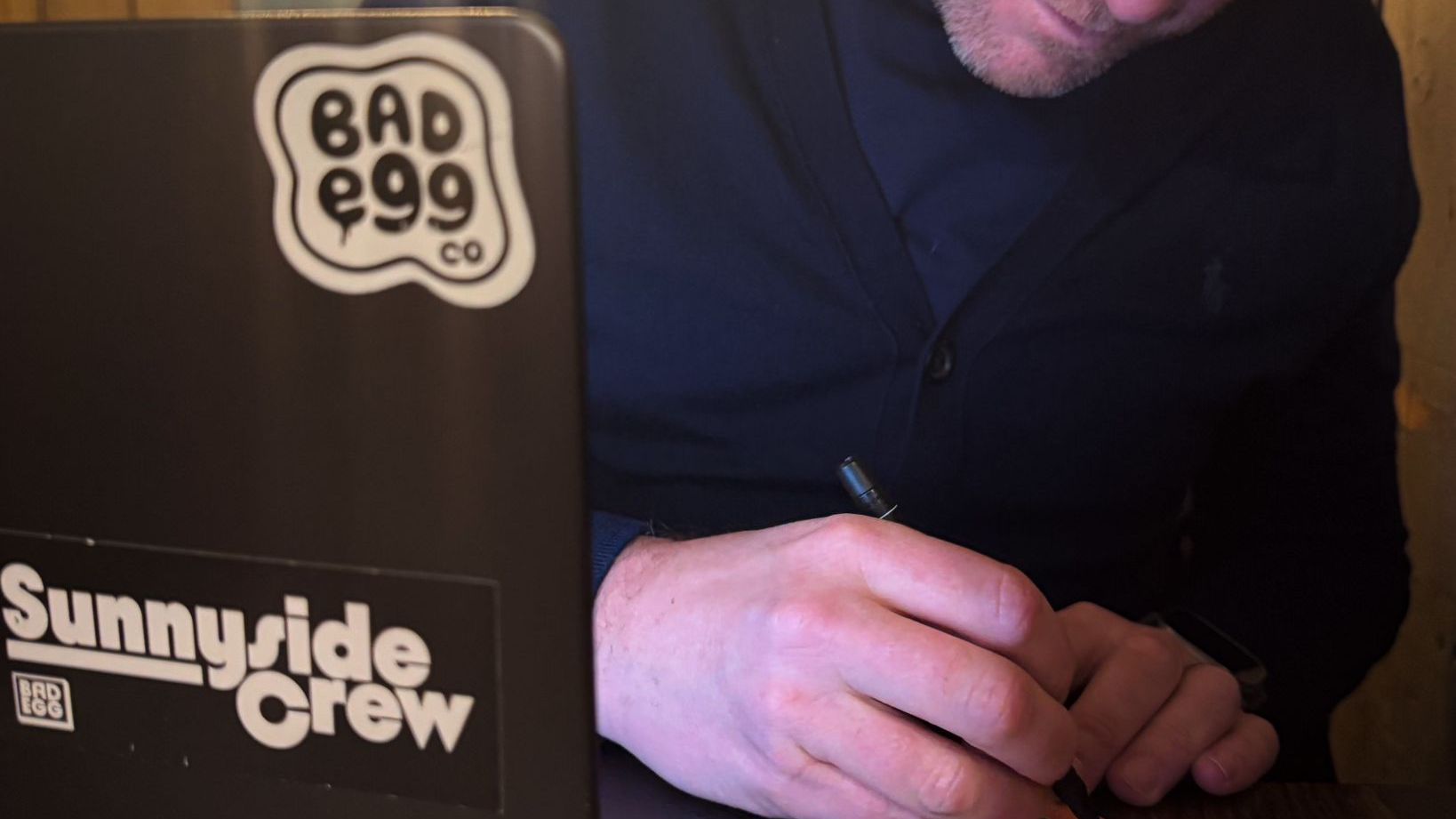 Person signing trading cards at a meeting table.