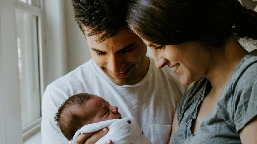 Young couple holding their newborn baby, representing new parents considering life insurance in Parker, CO