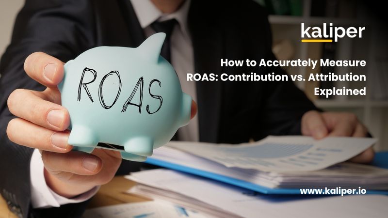 Blog header graphic titled "How to Accurately Measure ROAS: Contribution vs. Attribution Explained," showing a hand holding a light blue piggy bank labeled "ROAS" in front of a stack of papers.