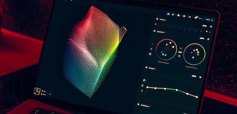 Close-up of a laptop screen at night displaying a colorful 3D waveform visualization with red ambient lighting, resembling an audio or signal monitoring interface.