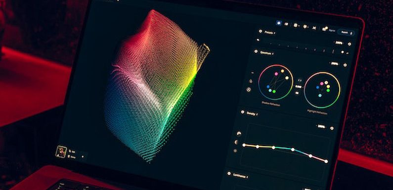 Close-up of a laptop screen at night displaying a colorful 3D waveform visualization with red ambient lighting, resembling an audio or signal monitoring interface.