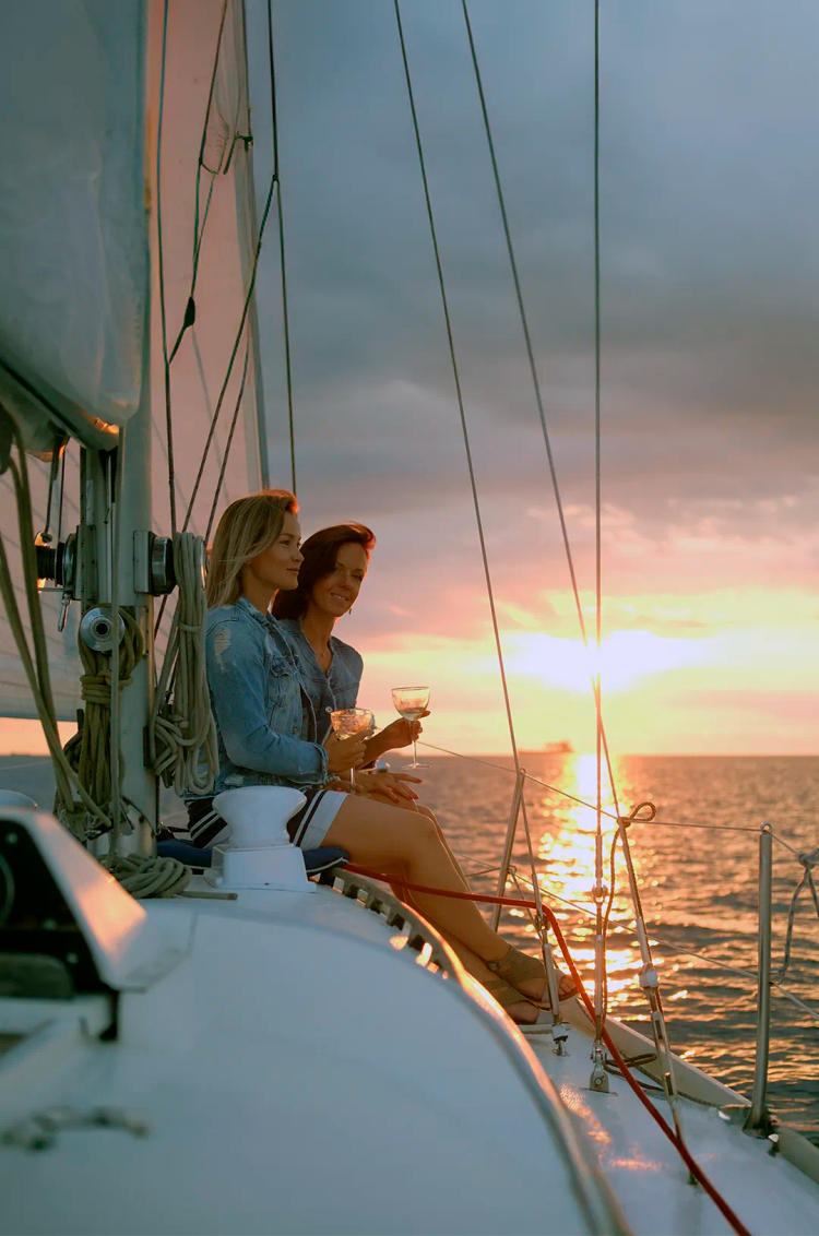 Friends on a sunset cruise in Puerto Vallarta, enjoying drinks and the view of the sun setting on the ocean.