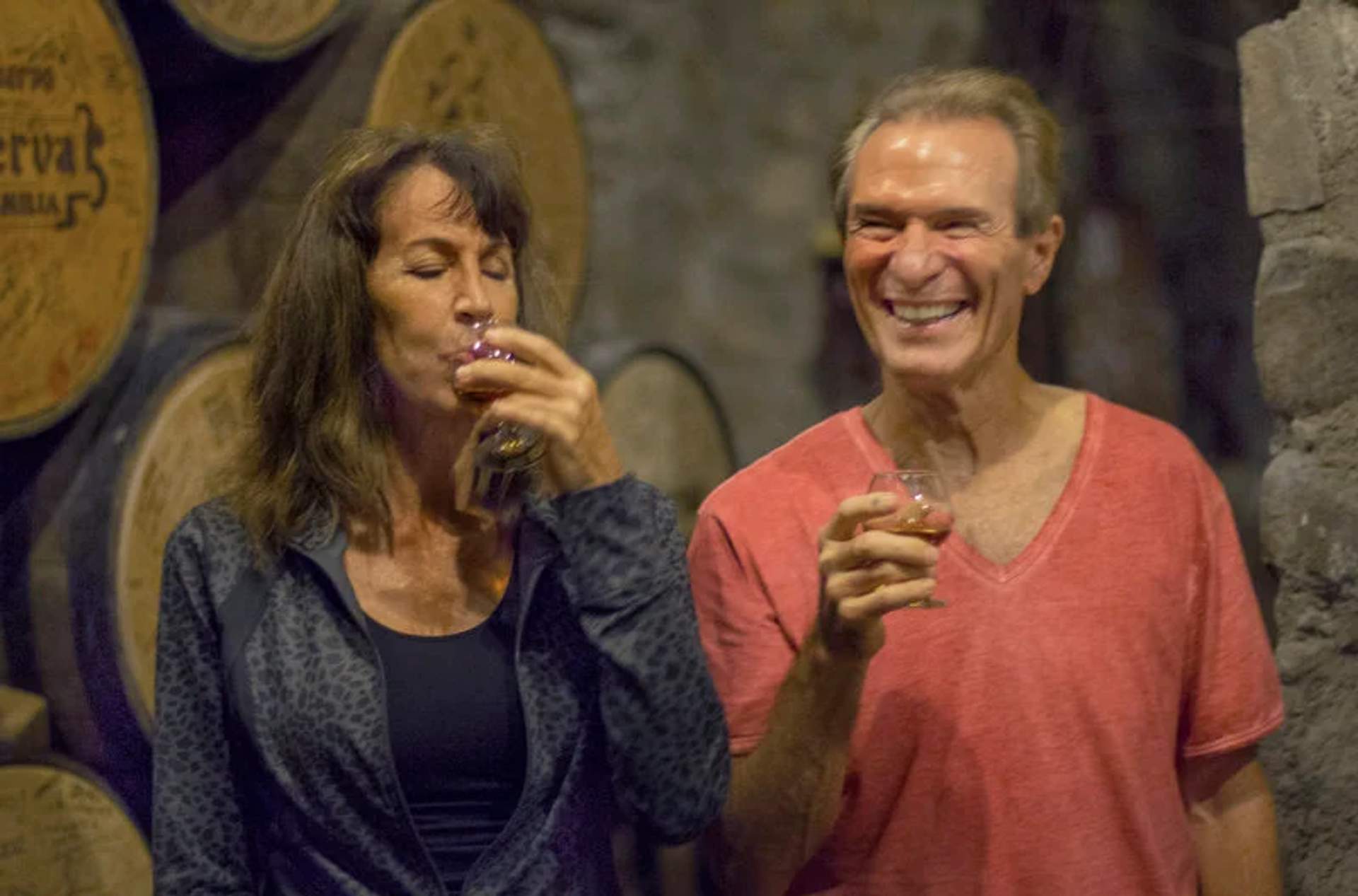 A couple enjoys a tequila tasting at Hacienda Jose Cuervo, with barrels in the background, in Tequila, Jalisco.
