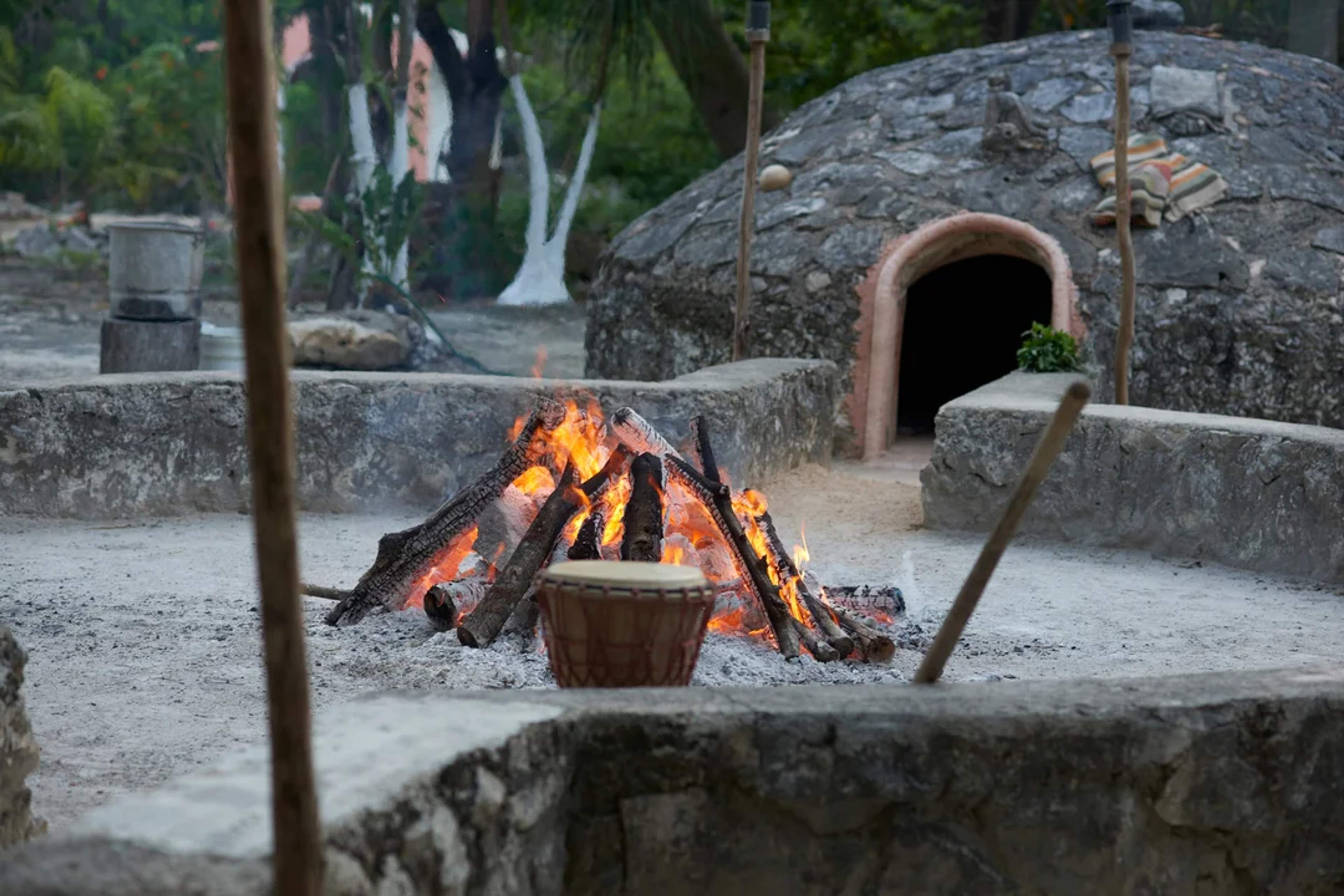 Sacred fire in front of a traditional temazcal dome, ready for a spiritual cleansing ritual.
