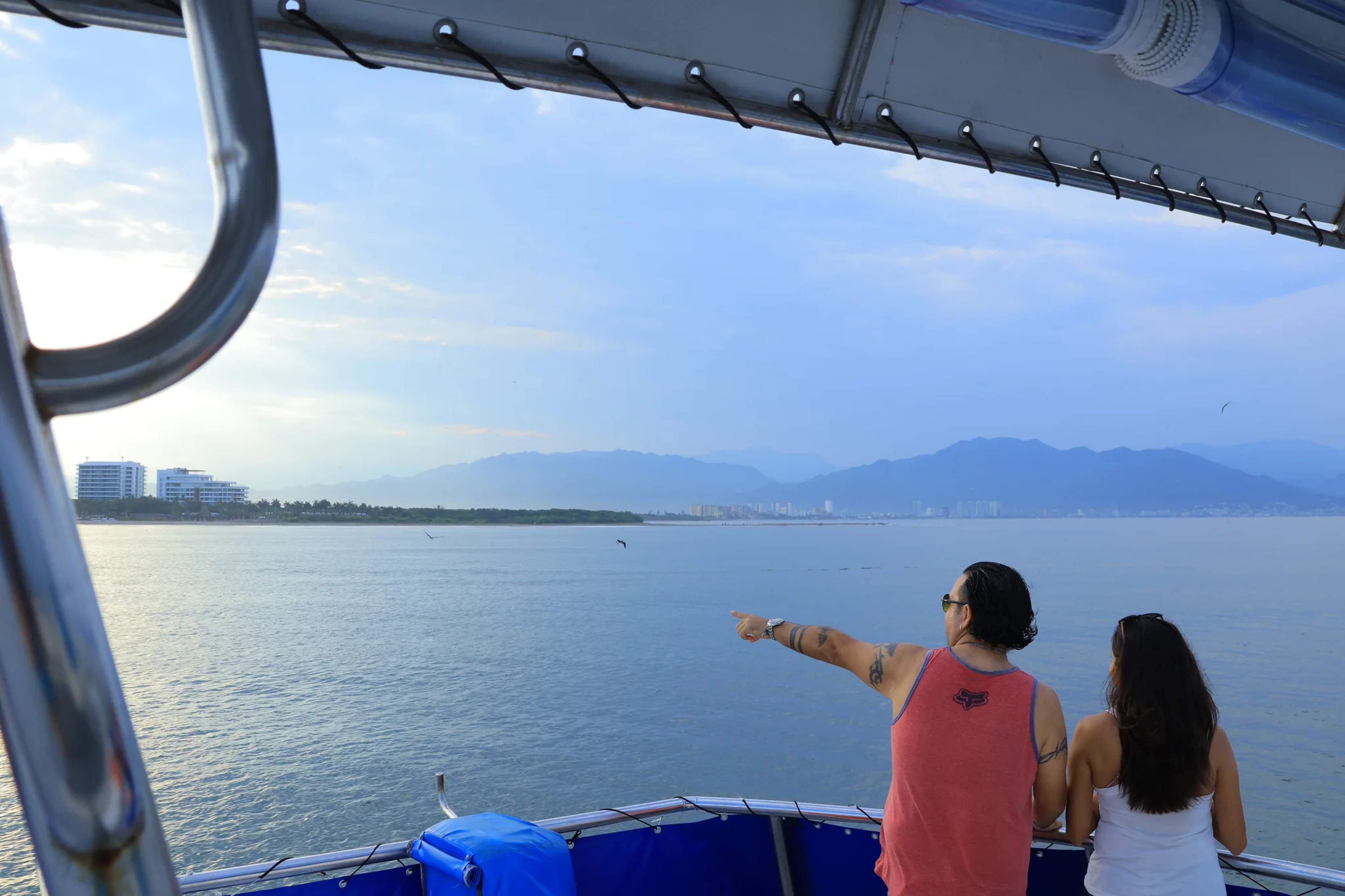 Pasajeros en un crucero de avistamiento de ballenas observan las tranquilas aguas del Pacífico y las montañas costeras cerca