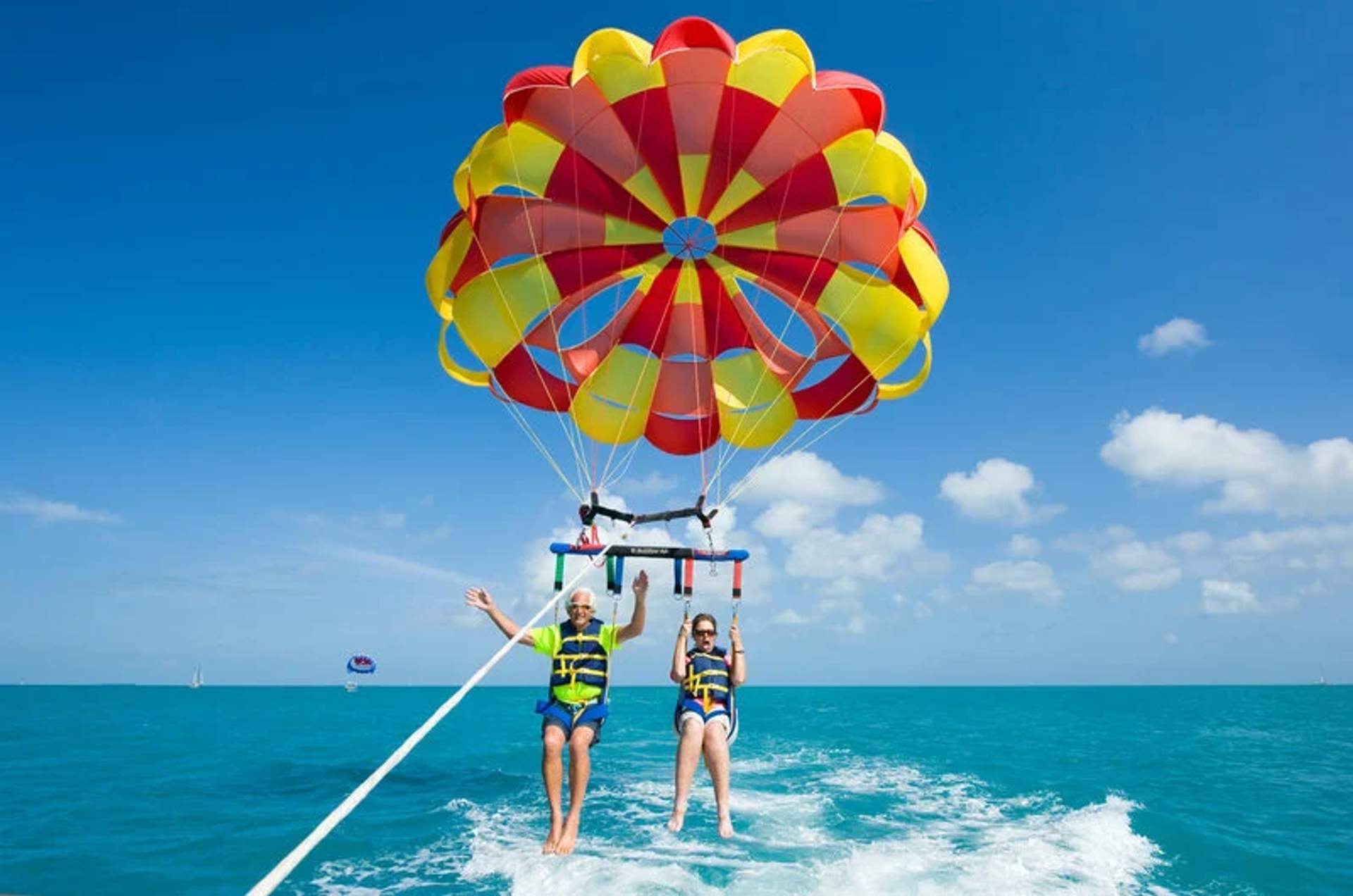 Two people parasailing over the ocean, enjoying the thrill and the view, with a colorful parachute at Las Caletas, Puerto Vallarta.