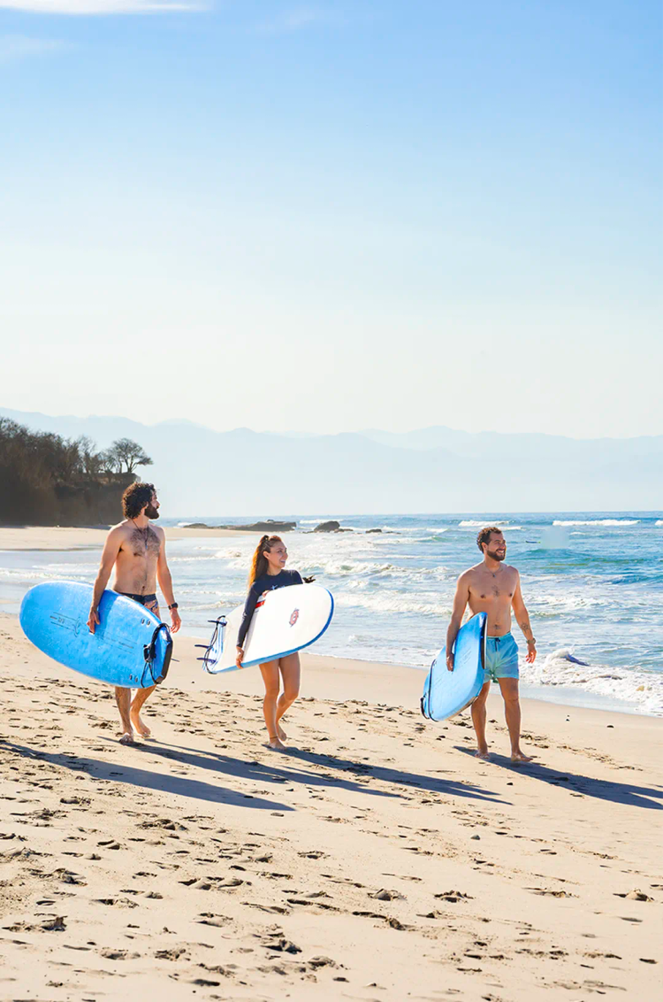 Guests carrying surfboards on Punta Mita Beach before a private surf lesson on the Pacific coast with Vallarta Adventures