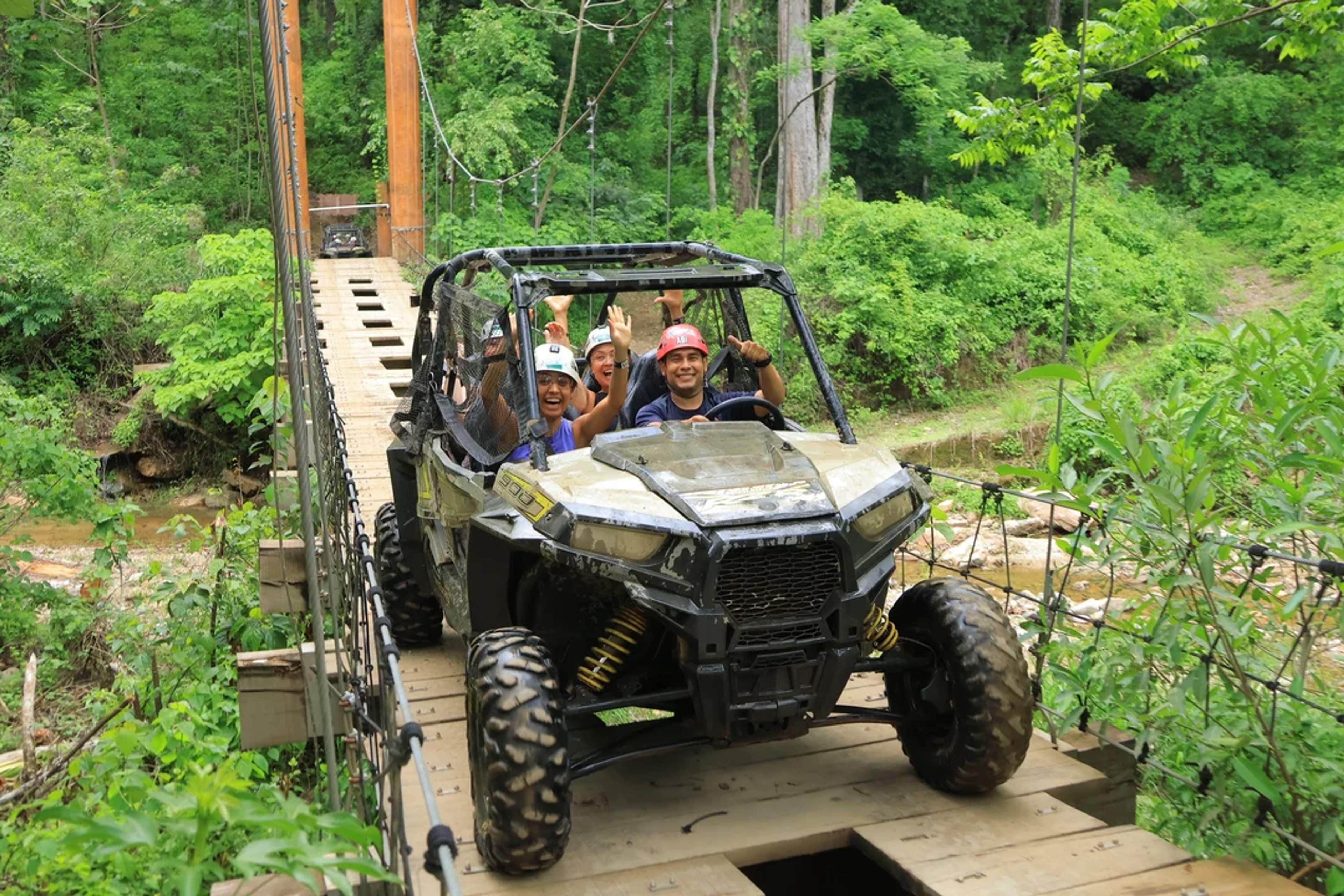 Adventurers cross a hanging jungle bridge in a UTV, laughing through a thrilling off-road ride.