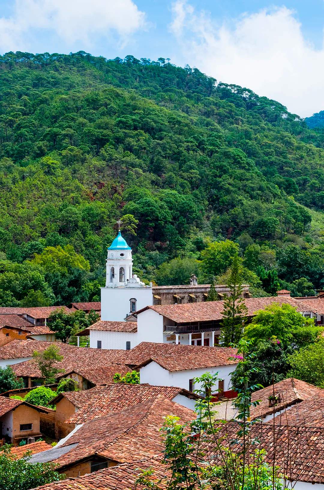 Aerial view of San Sebastian del Oeste, featuring its iconic white church with a blue dome amidst the Sierra Madre mountains.