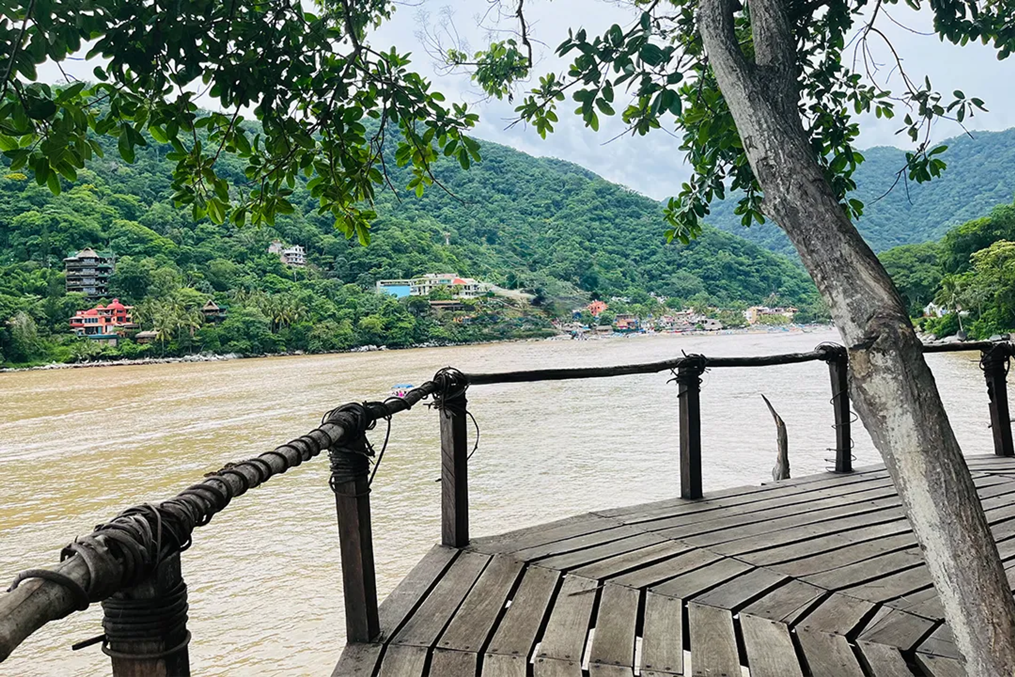 Mirador de madera con vista al río Horcones y Boca de Tomatlán, rodeado de colinas verdes.