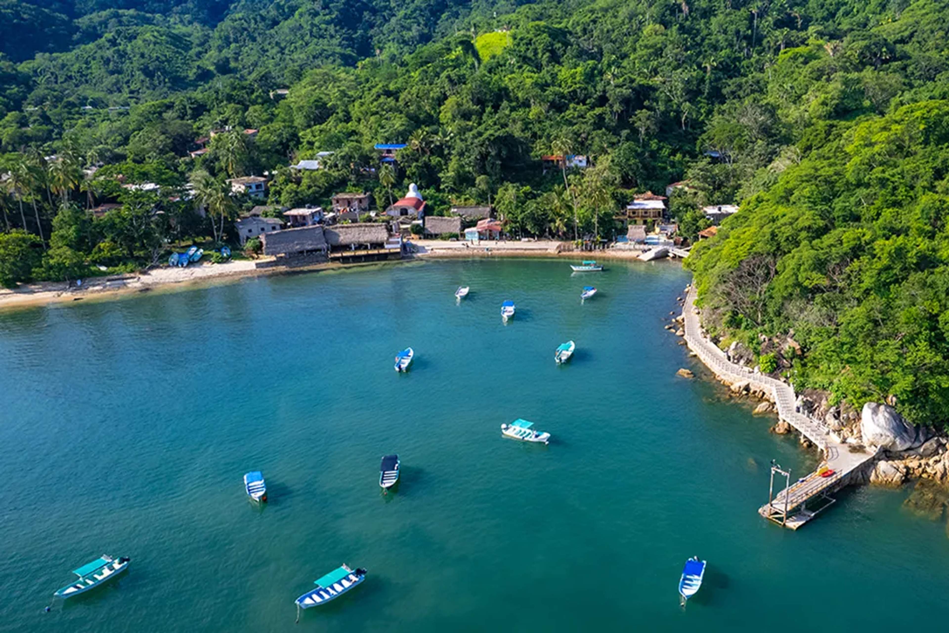 Vista aérea de lanchas ancladas en una bahía tranquila rodeada de selva de Quimixto.