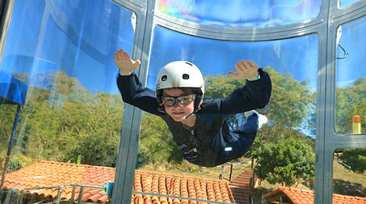 Un niño con casco y gafas disfruta del paracaidismo interior en un túnel de viento, experimentando la emoción de volar.