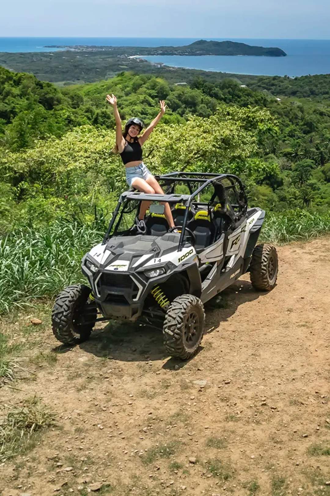 Woman on a Punta Mita ATV tour at a scenic viewpoint overlooking the ocean near Sayulita, Mexico.