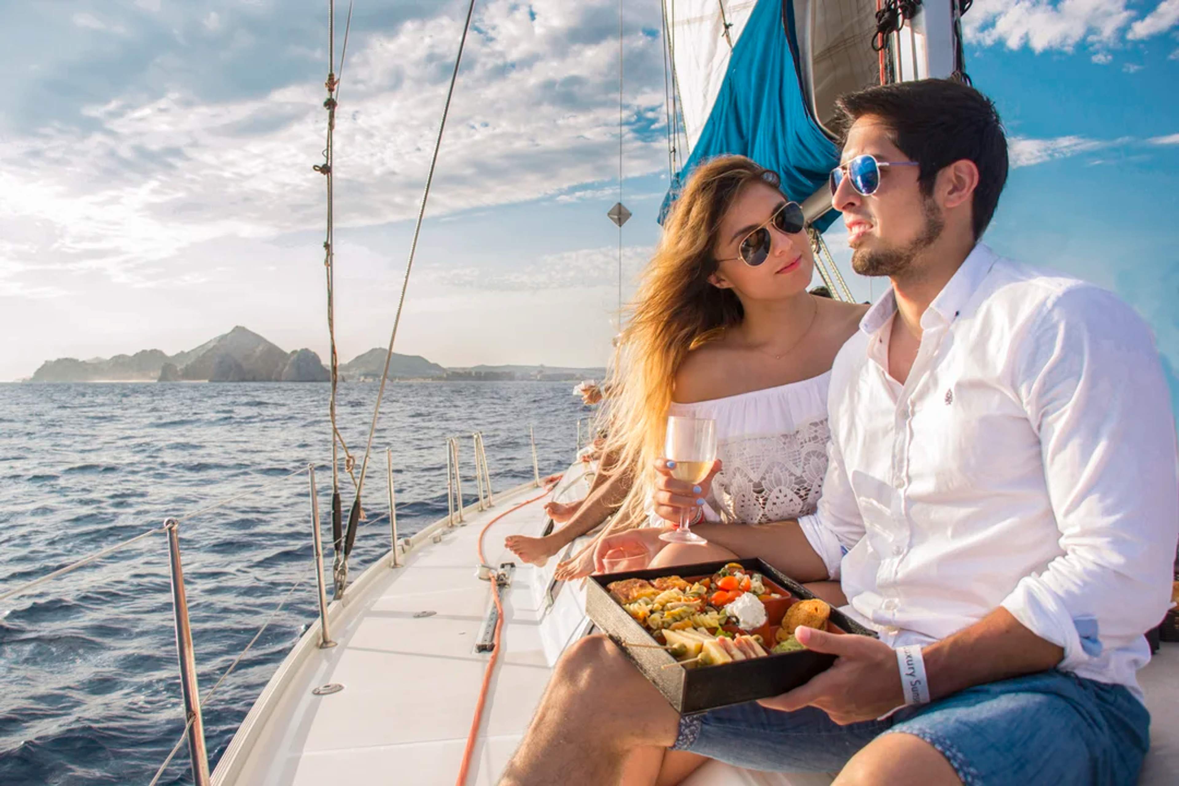 A couple enjoys a luxury sailing experience with wine and gourmet food in Cabo San Lucas.