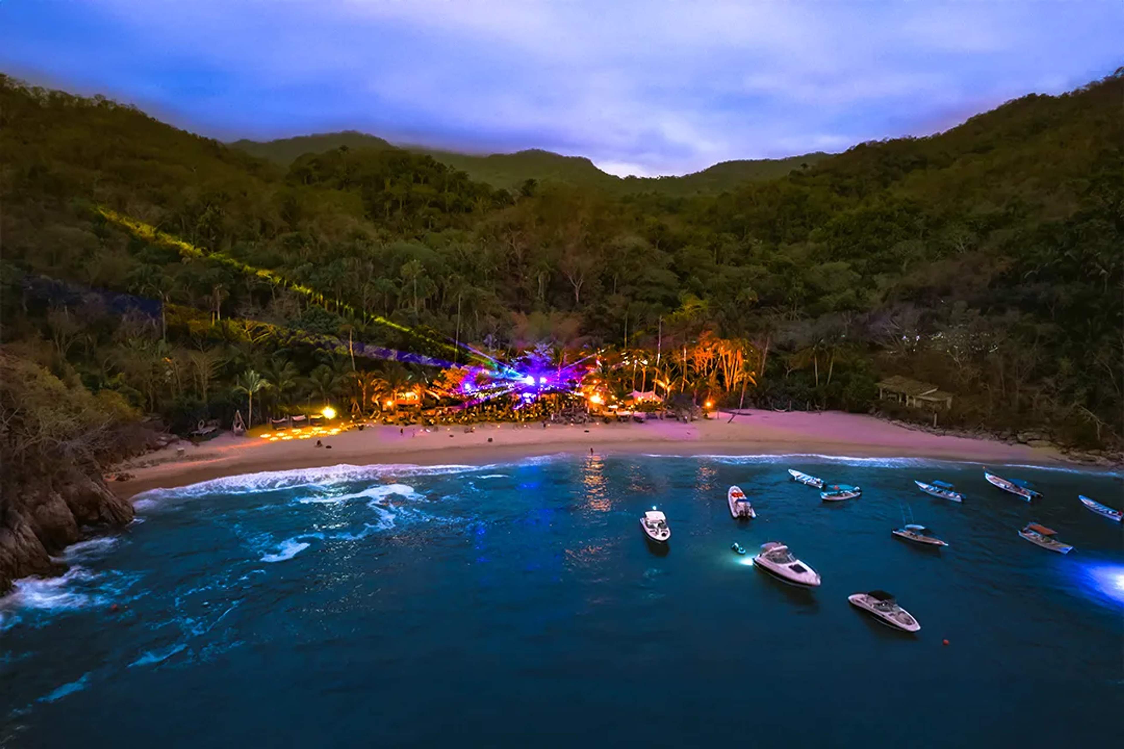 Majahuitas beach party in Puerto Vallarta at night with lights, music, boats, and jungle setting