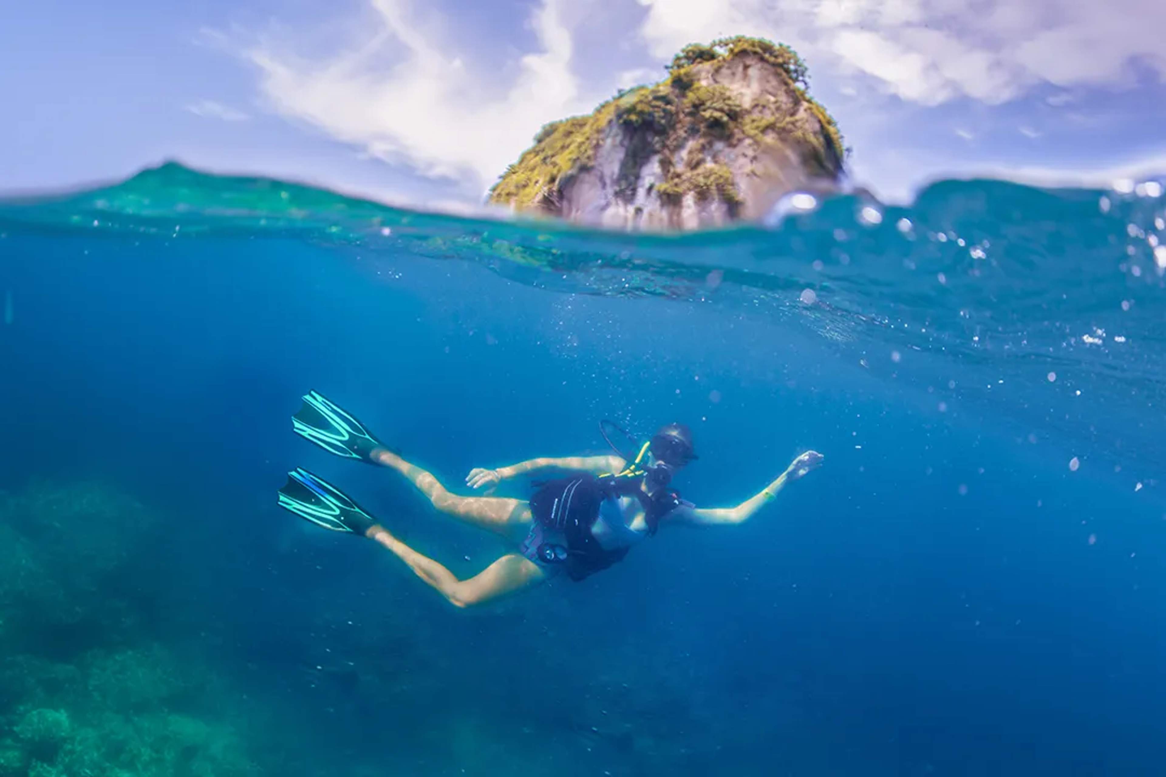 Scuba diver glides through clear waters near rocky islets, enjoying an underwater adventure at Los Arcos, in Puerto Vallarta.