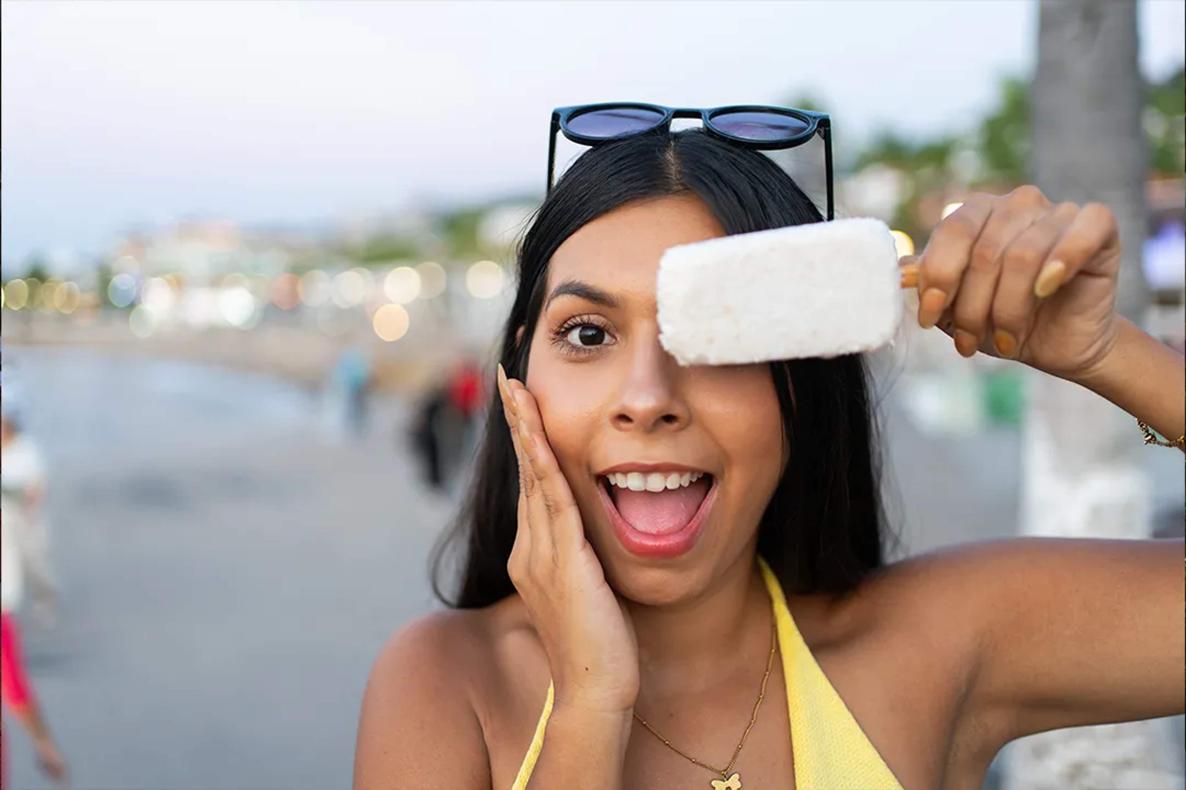 Woman enjoying traditional Mexican coconut popsicle on Puerto Vallarta beach at sunset
