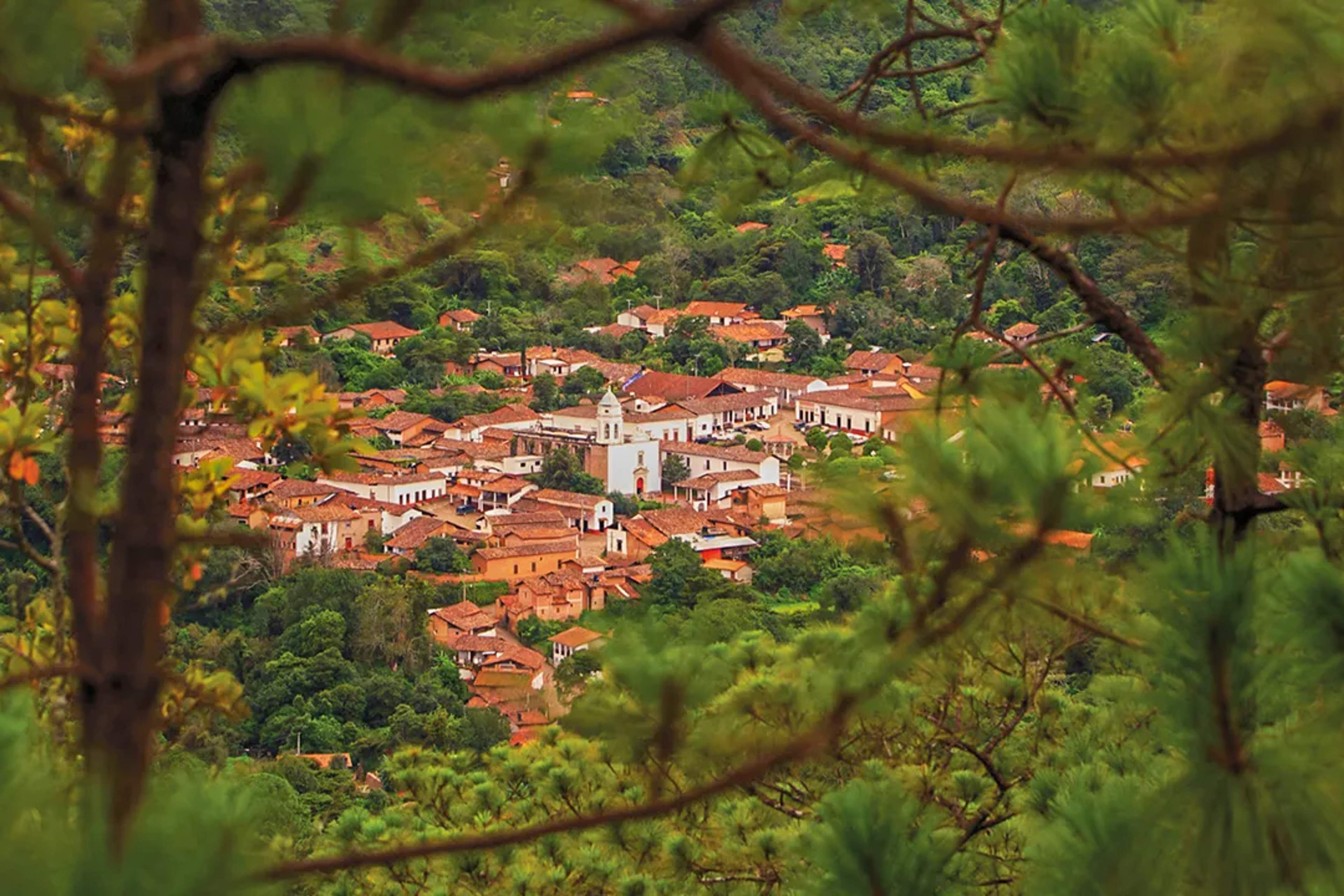 Vista escénica del pintoresco pueblo de San Sebastian del Oeste con techos rojos y bosque alrededor.