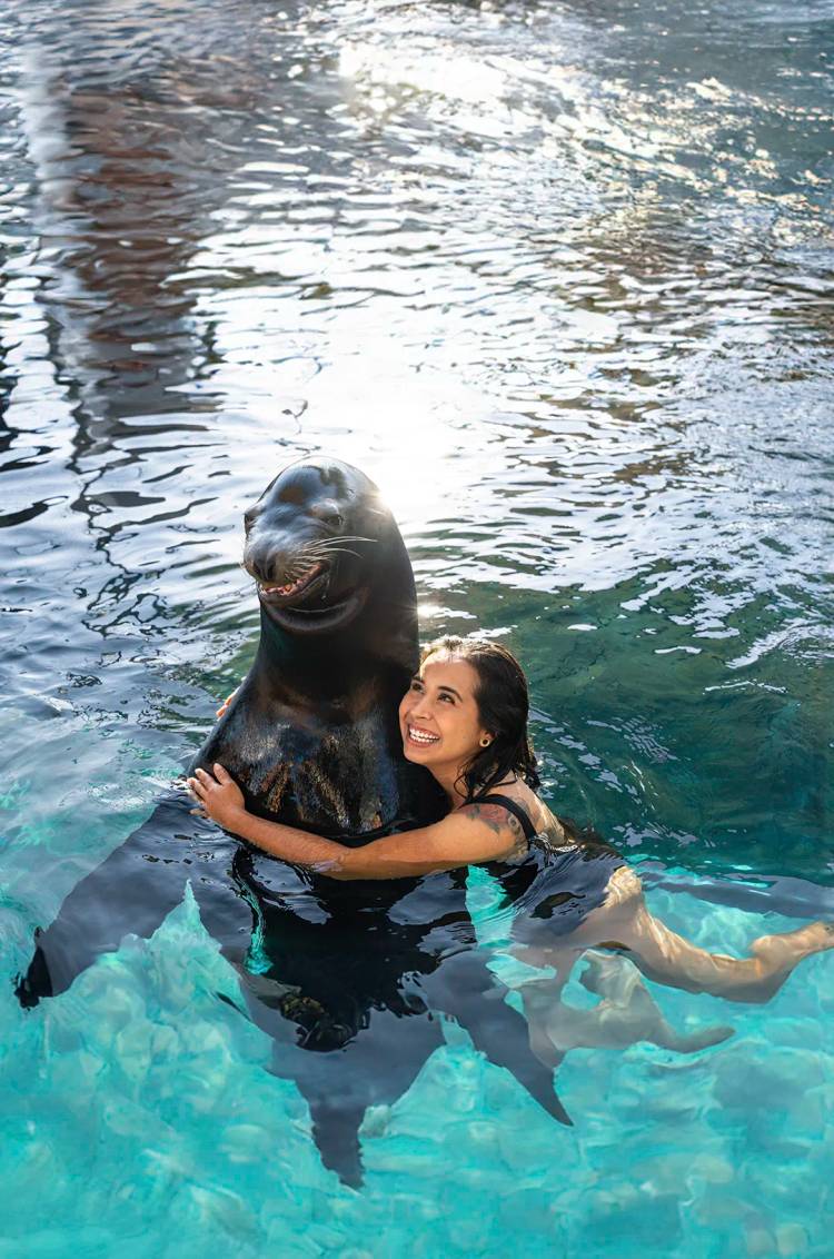 Woman joyfully hugging a sea lion at OceanMania waterpark.