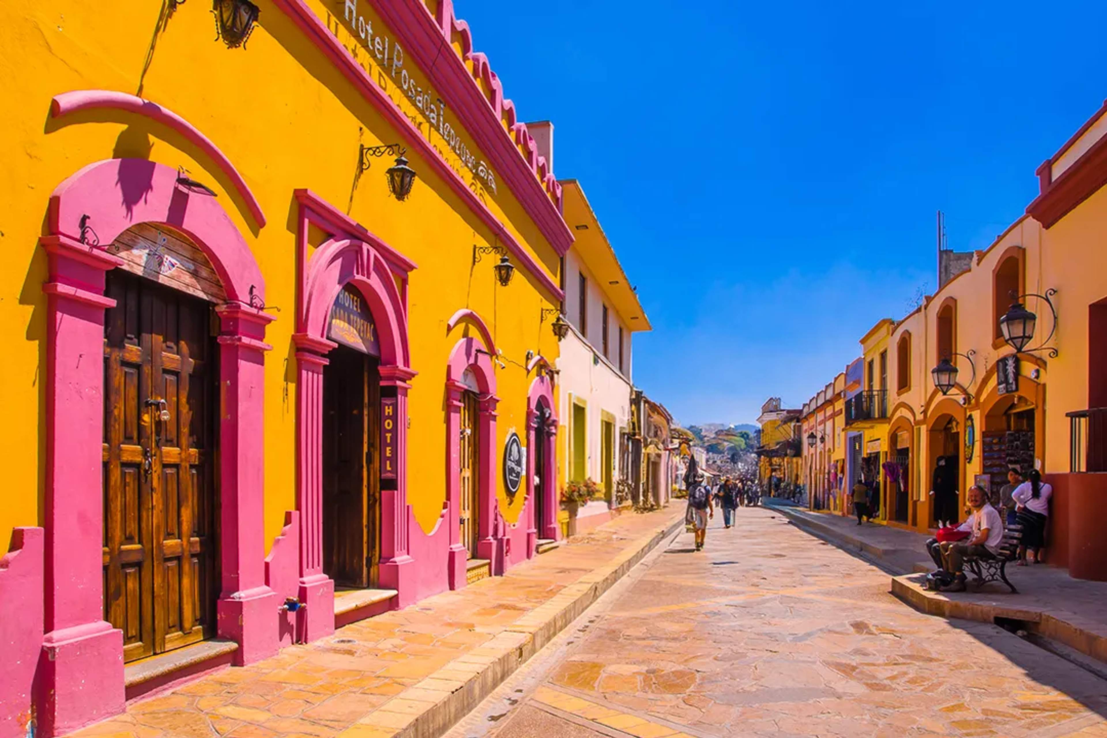 Colorida calle colonial de San Cristóbal de las Casas, Chiapas, con edificios tradicionales y comercios.