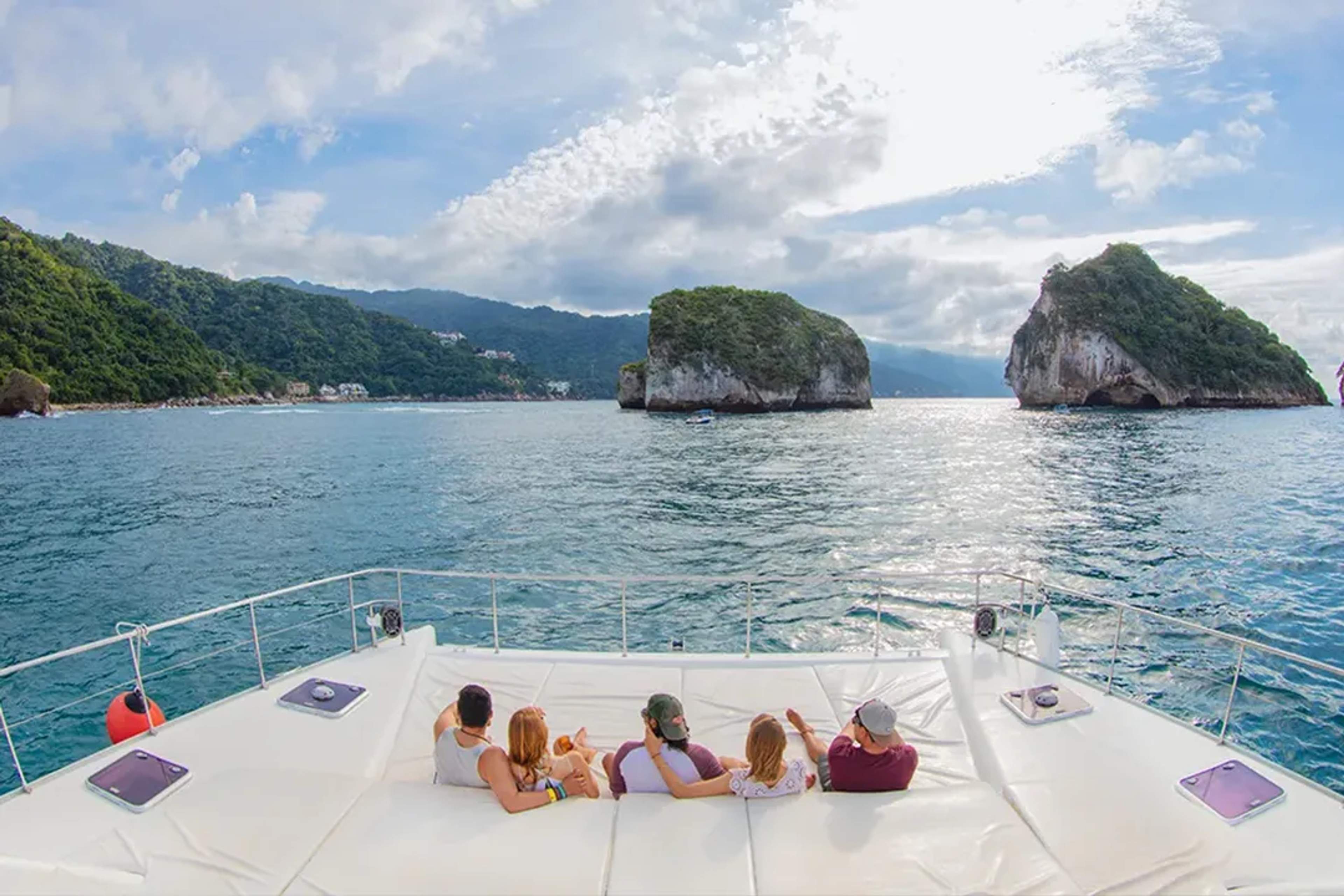 Un grupo descansa en un yate, admirando las formaciones rocosas de Los Arcos en Vallarta.