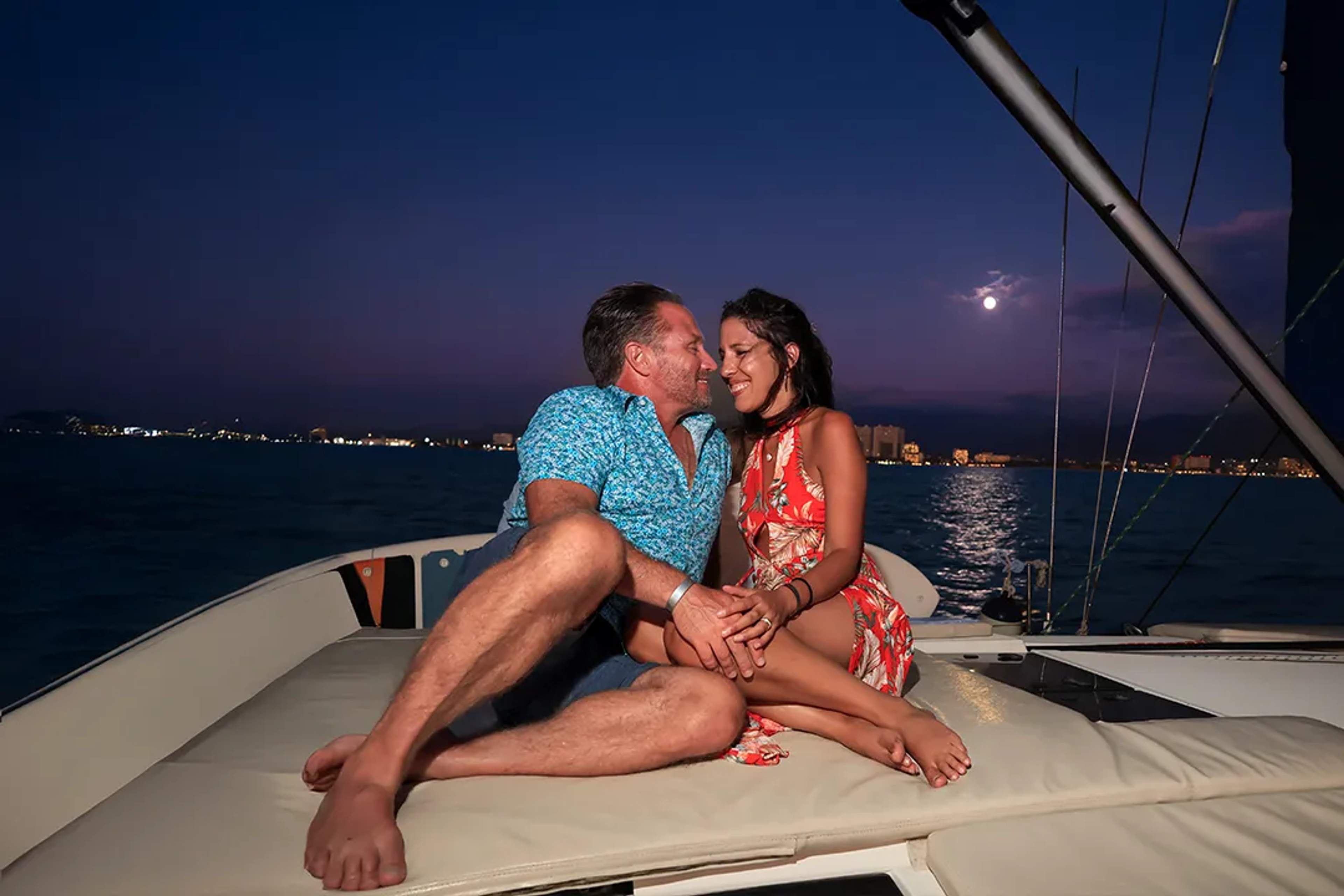 Romantic sunset sailing tour in Puerto Vallarta, couple under full moon on luxury catamaran.