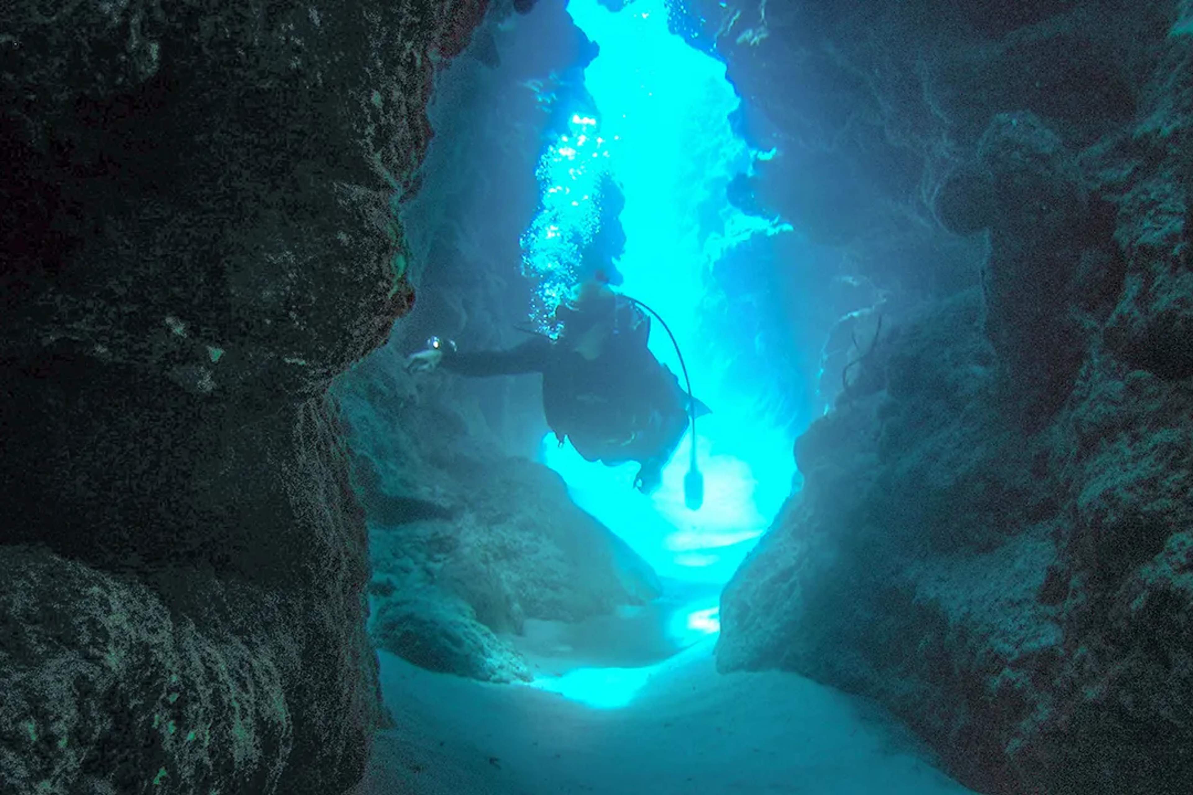 Scuba diver explores an underwater cave, illuminated by beams of light in the crystal-clear waters o Marietas, in Puerto Vallarta.