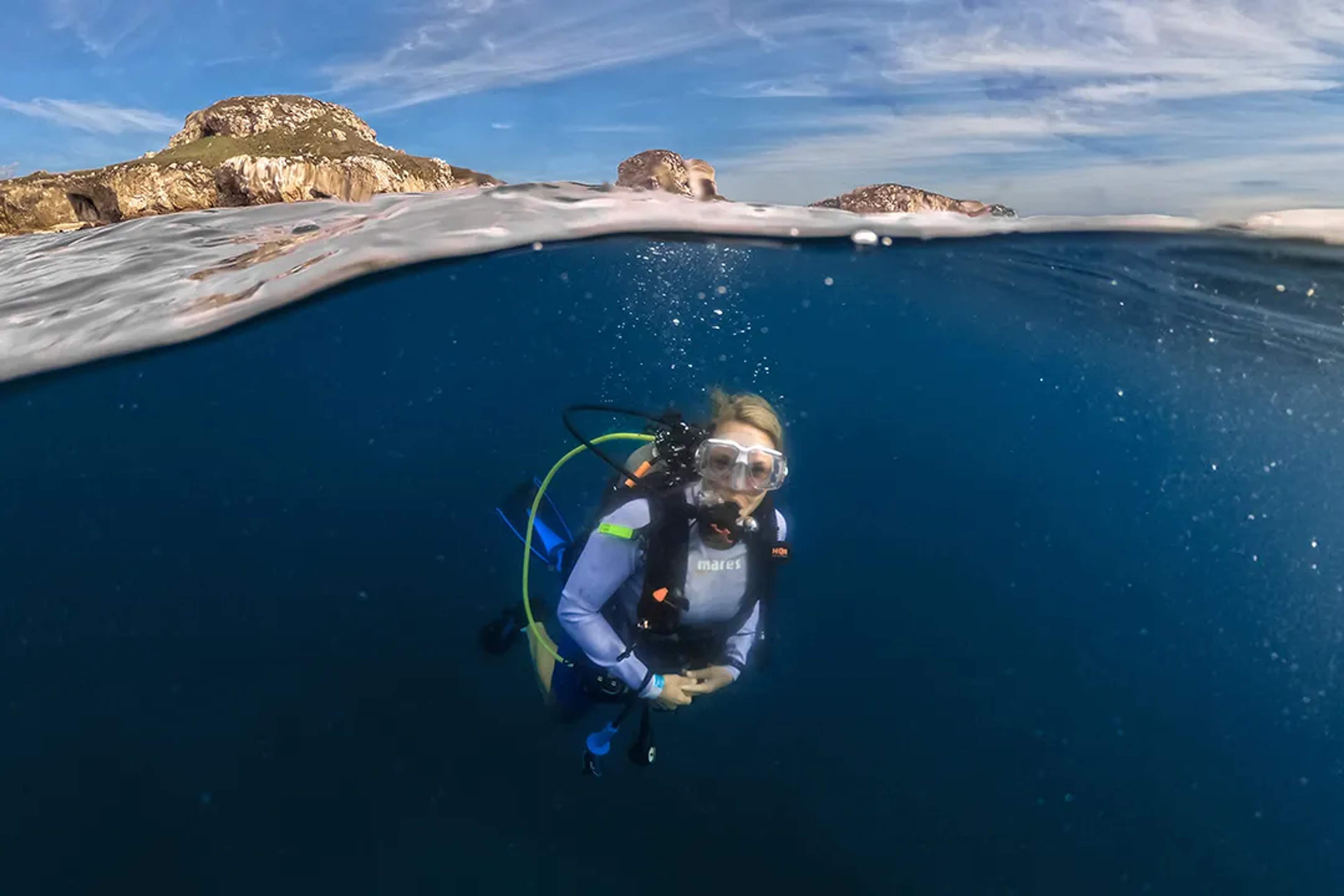 Diver enjoying crystal-clear waters near rocky islands, captured above and below the surface at Las Marietas