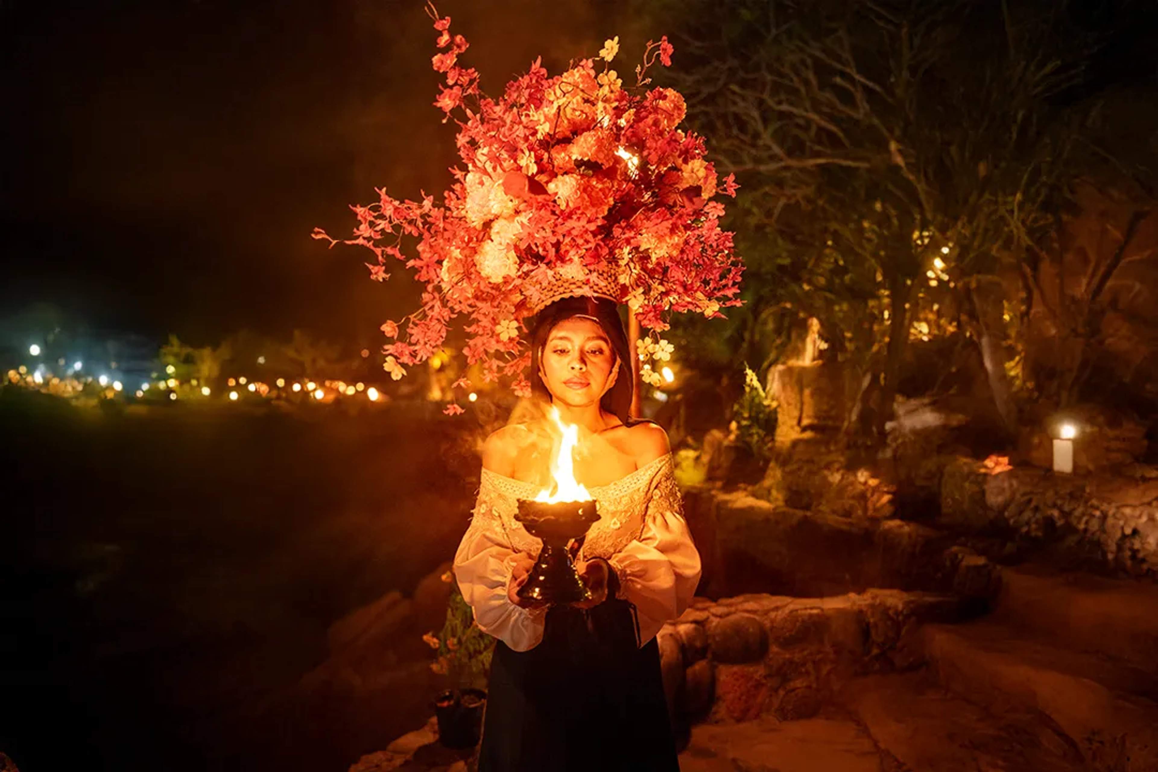 Rhythms of the Night performer at Las Caletas with candlelight, floral costume and immersive jungle path