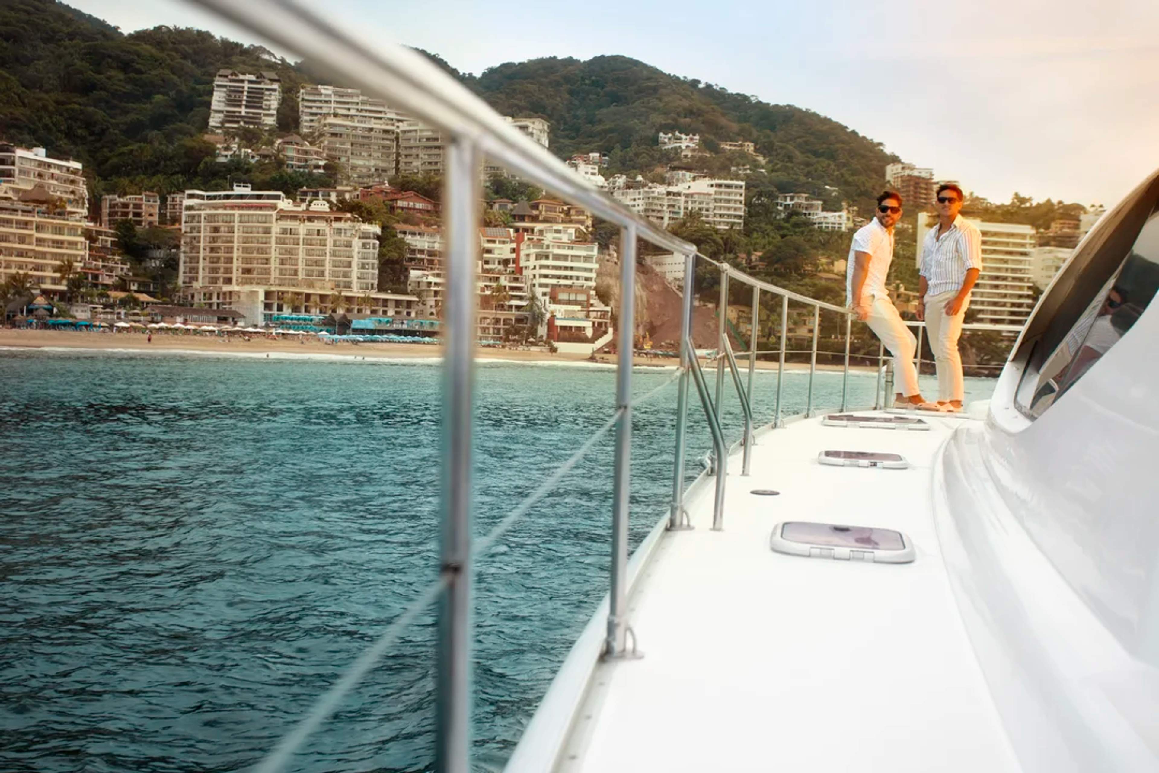 Pareja disfruta un paseo en yate frente a la costa de Puerto Vallarta al atardecer.