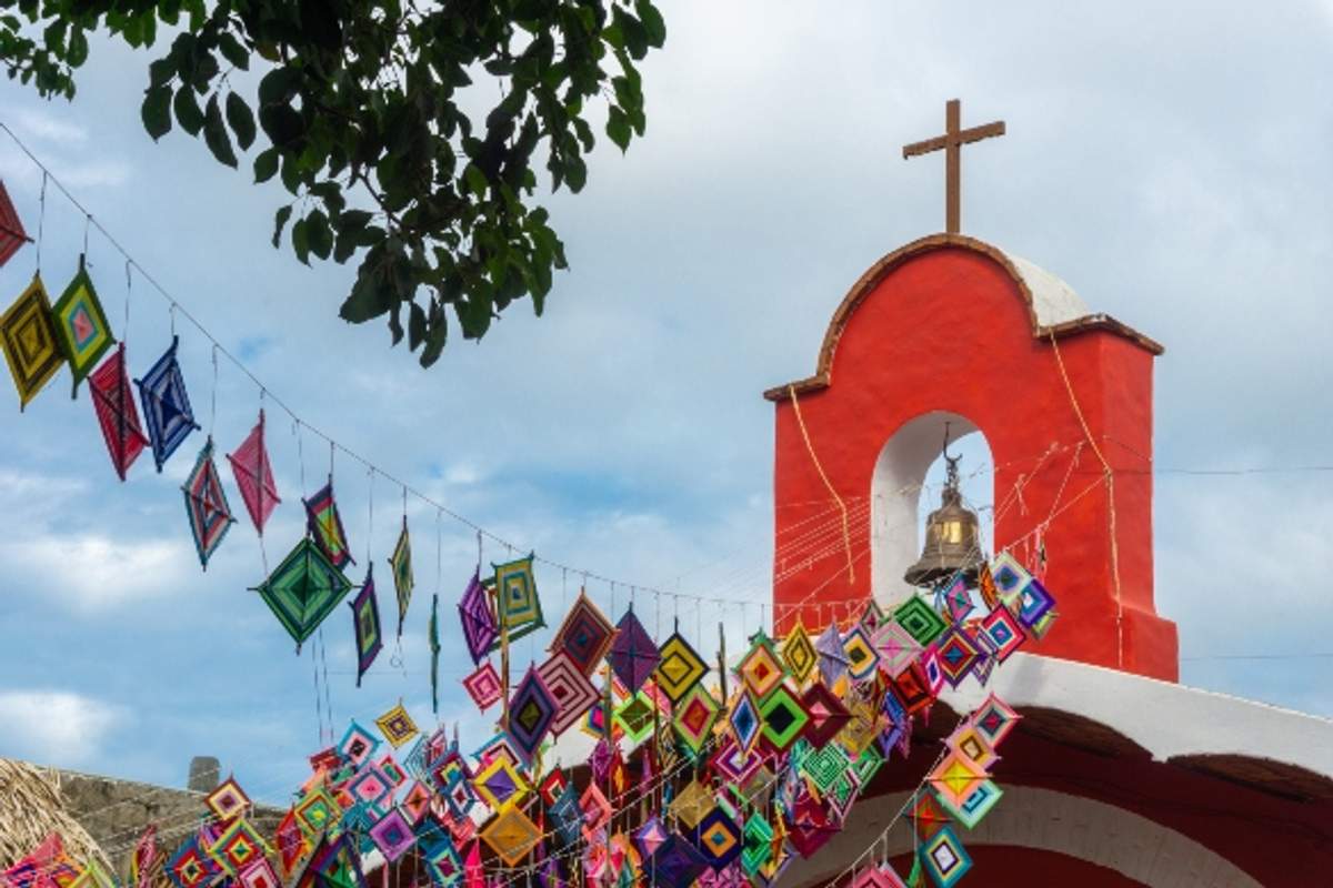  Sayulita church adorned with colorful "ojos de Dios" decorations, showcasing a blend of Huichol and Catholic heritage.