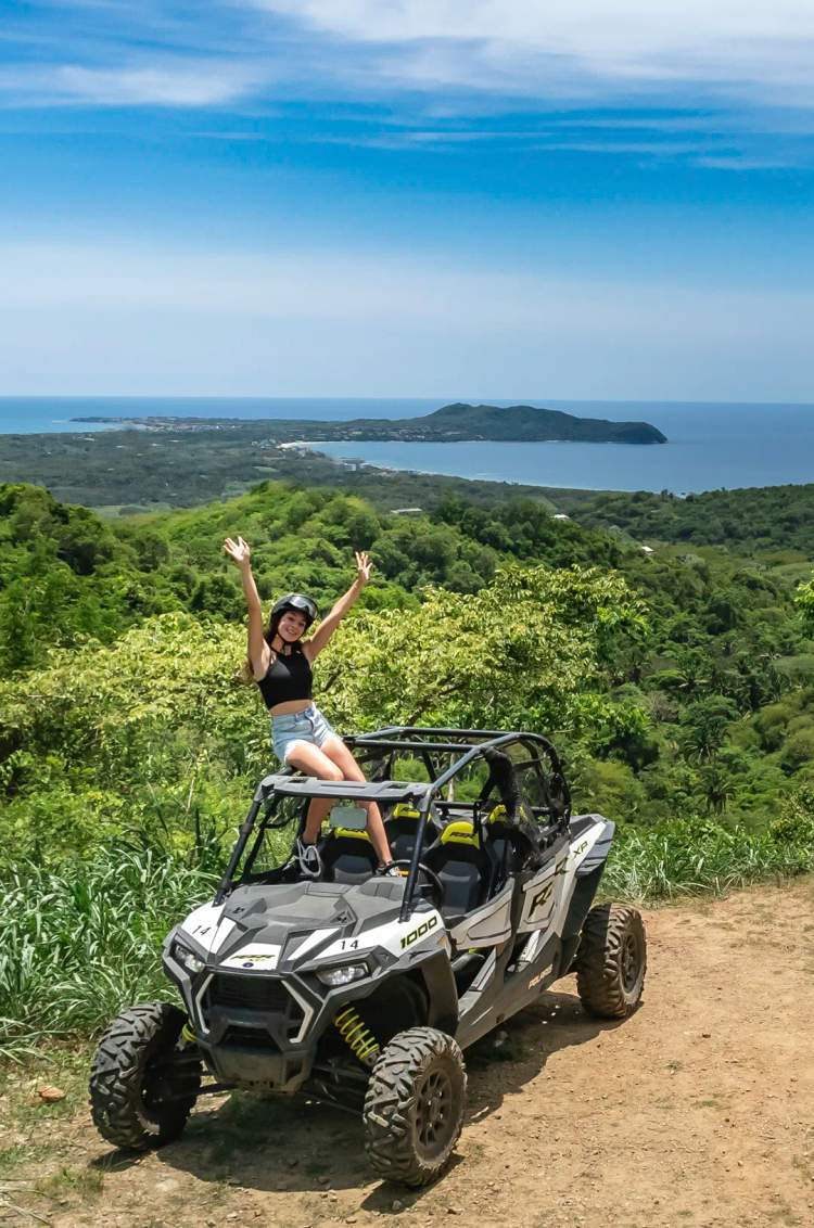 Woman on a Punta Mita ATV tour at a scenic viewpoint overlooking the ocean near Sayulita, Mexico.