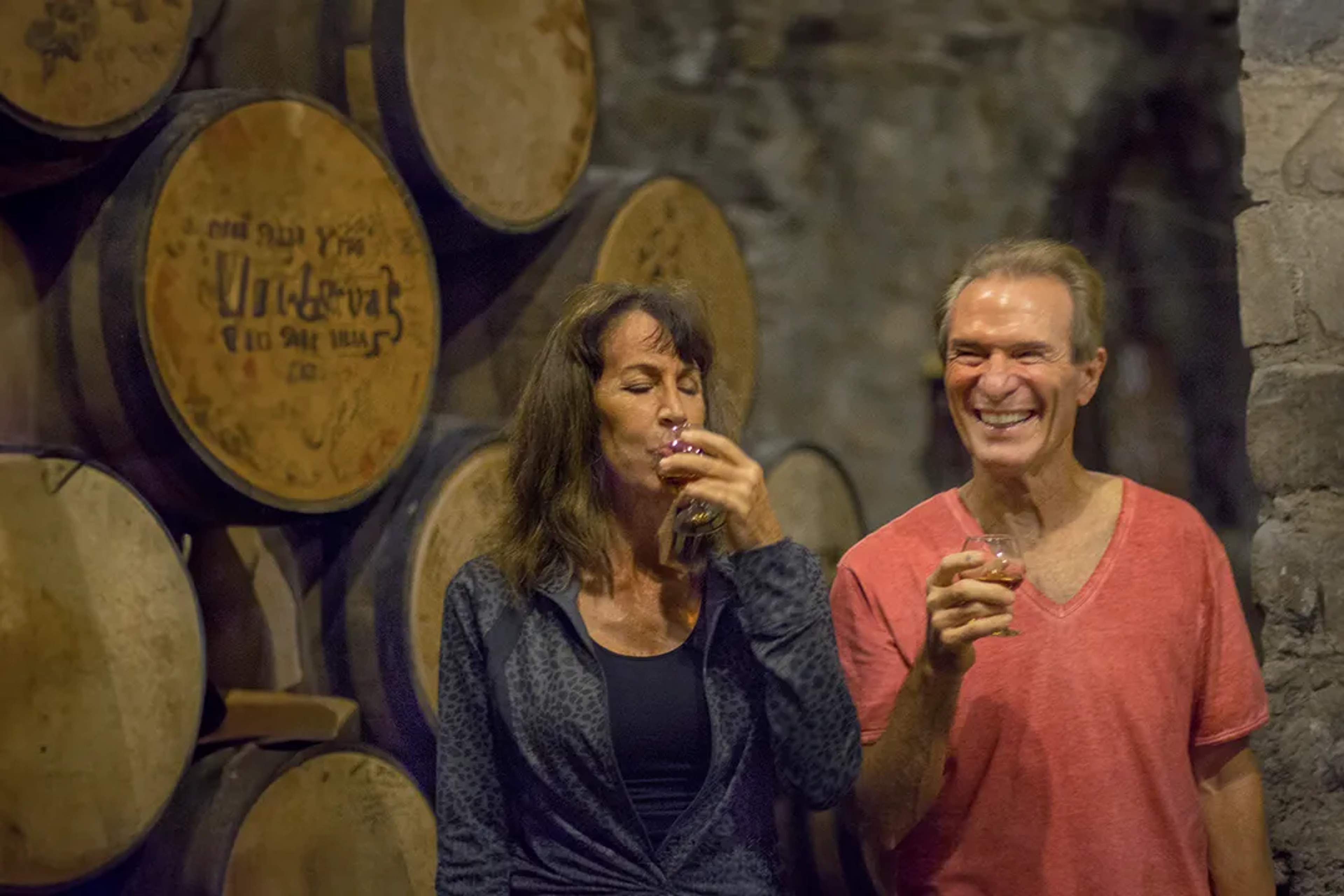 Couple enjoying a tequila tasting inside a rustic cellar, surrounded by aging oak barrels.
