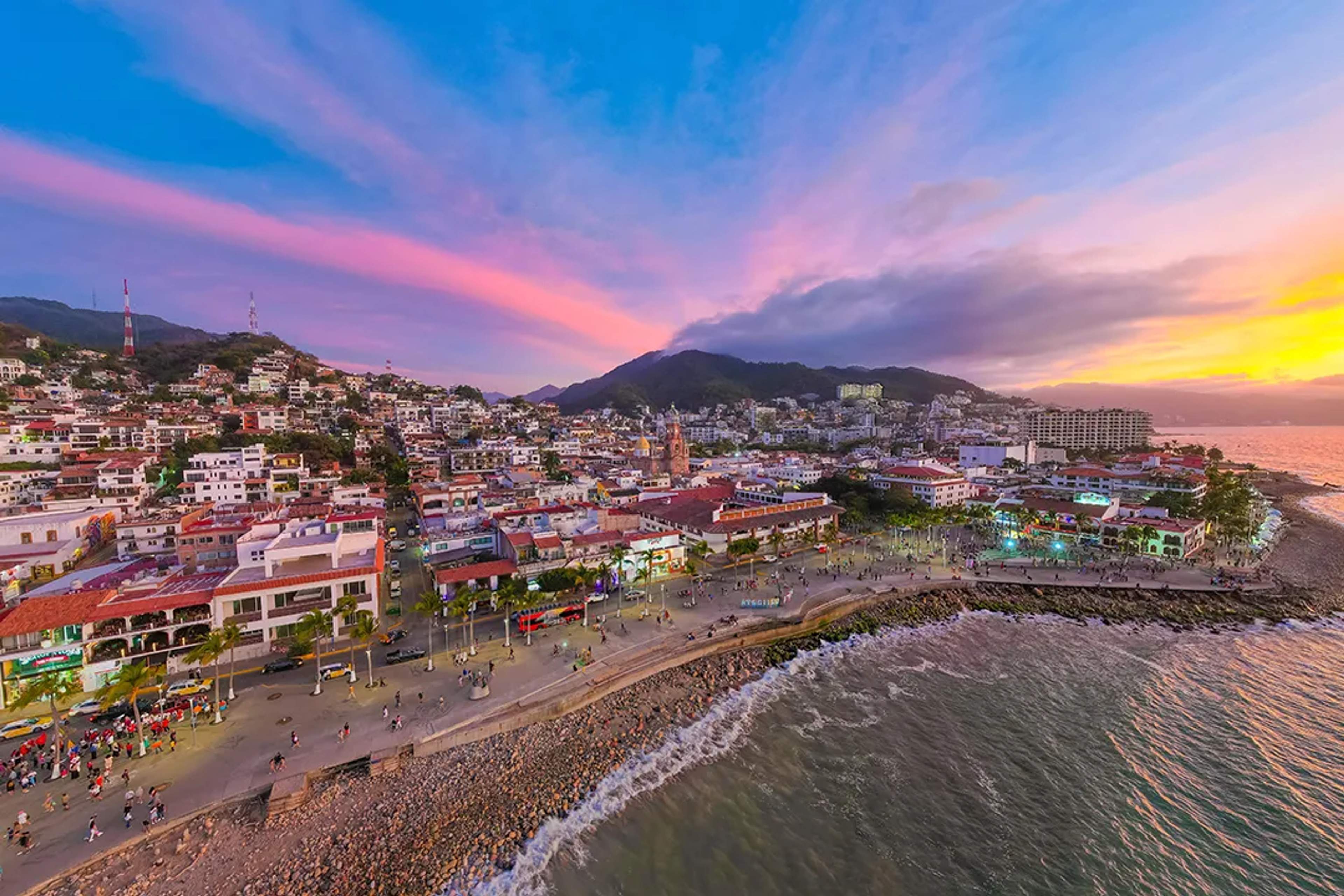 Puerto Vallarta Malecón at sunset, oceanfront promenade and Old Town city skyline view.