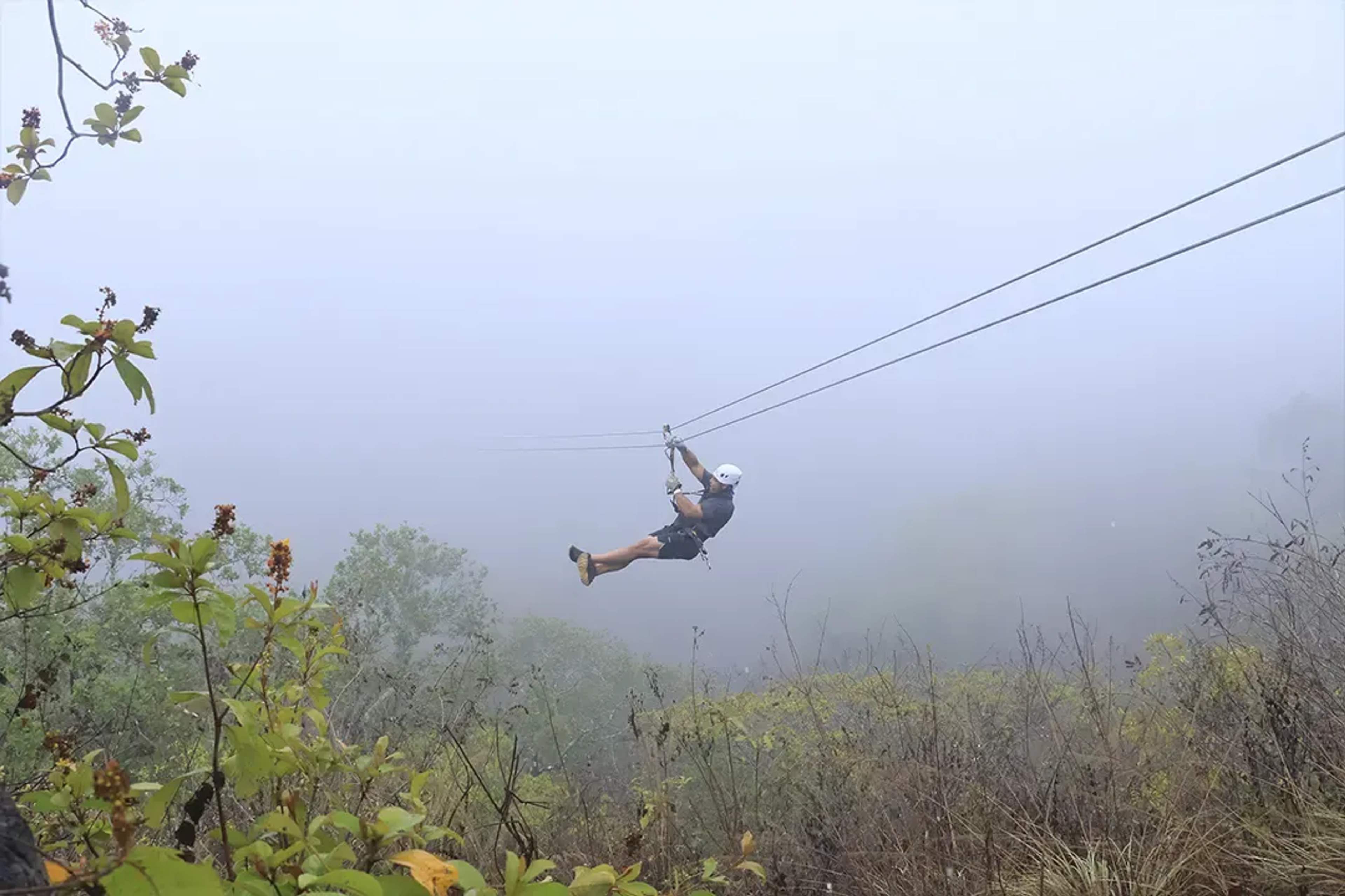 Persona en tirolesa atraviesa la selva entre neblina en las montañas de la Sierra Madre.