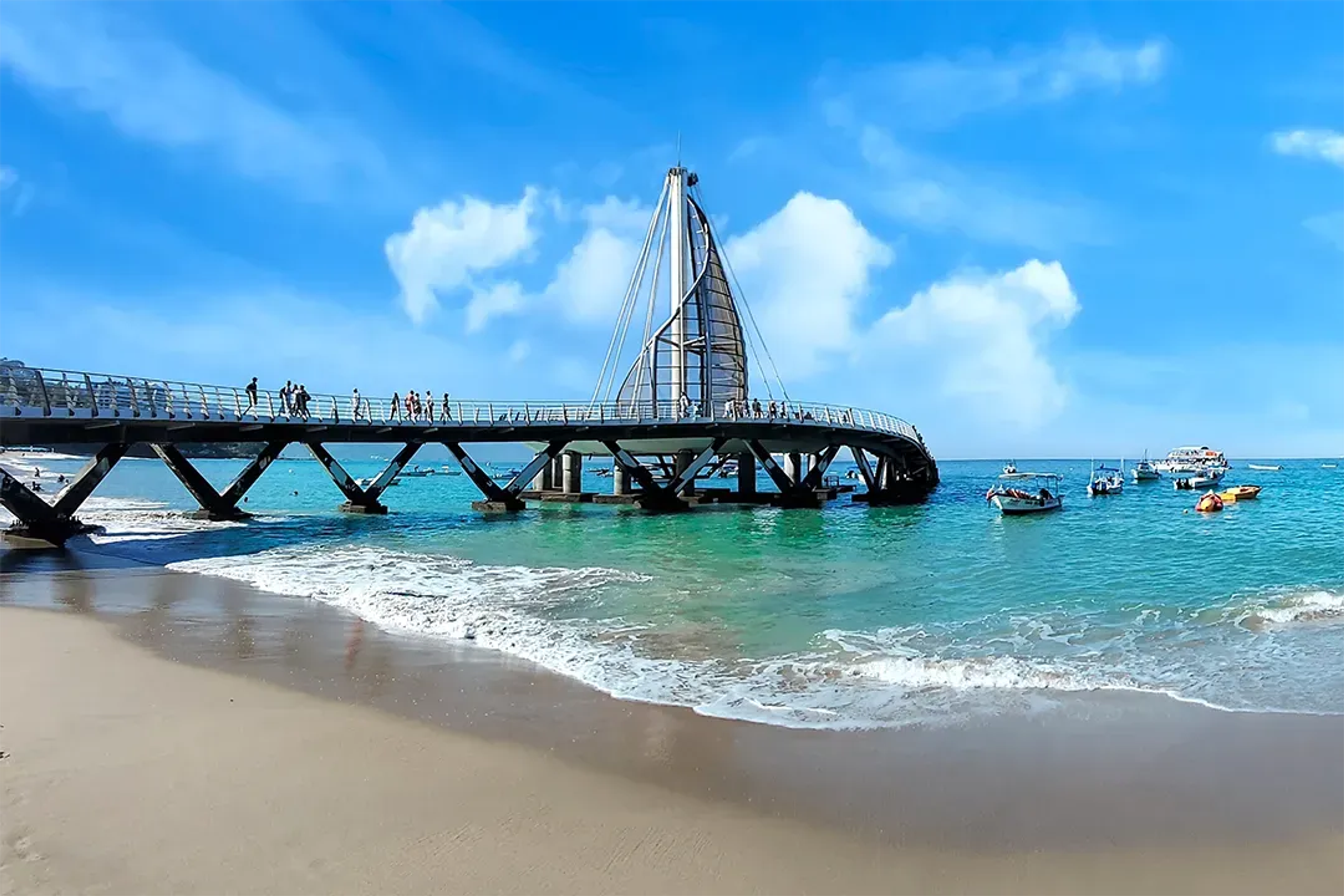 Los Muertos Pier stands over turquoise waters and blue skies on a sunny Puerto Vallarta beach.