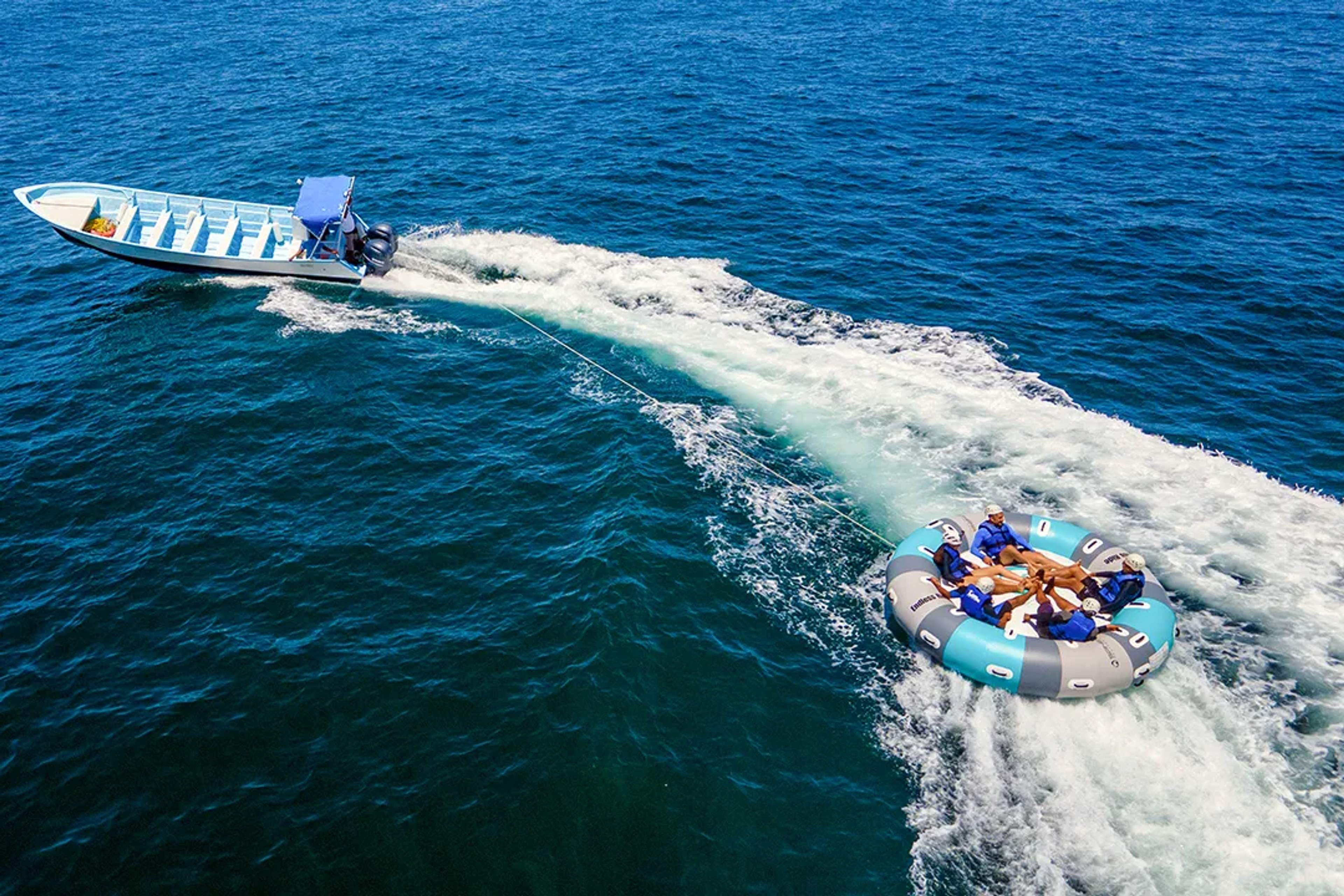 Boat towing a circular inflatable with guests enjoying an exciting water ride in Puerto Vallarta, Mexico