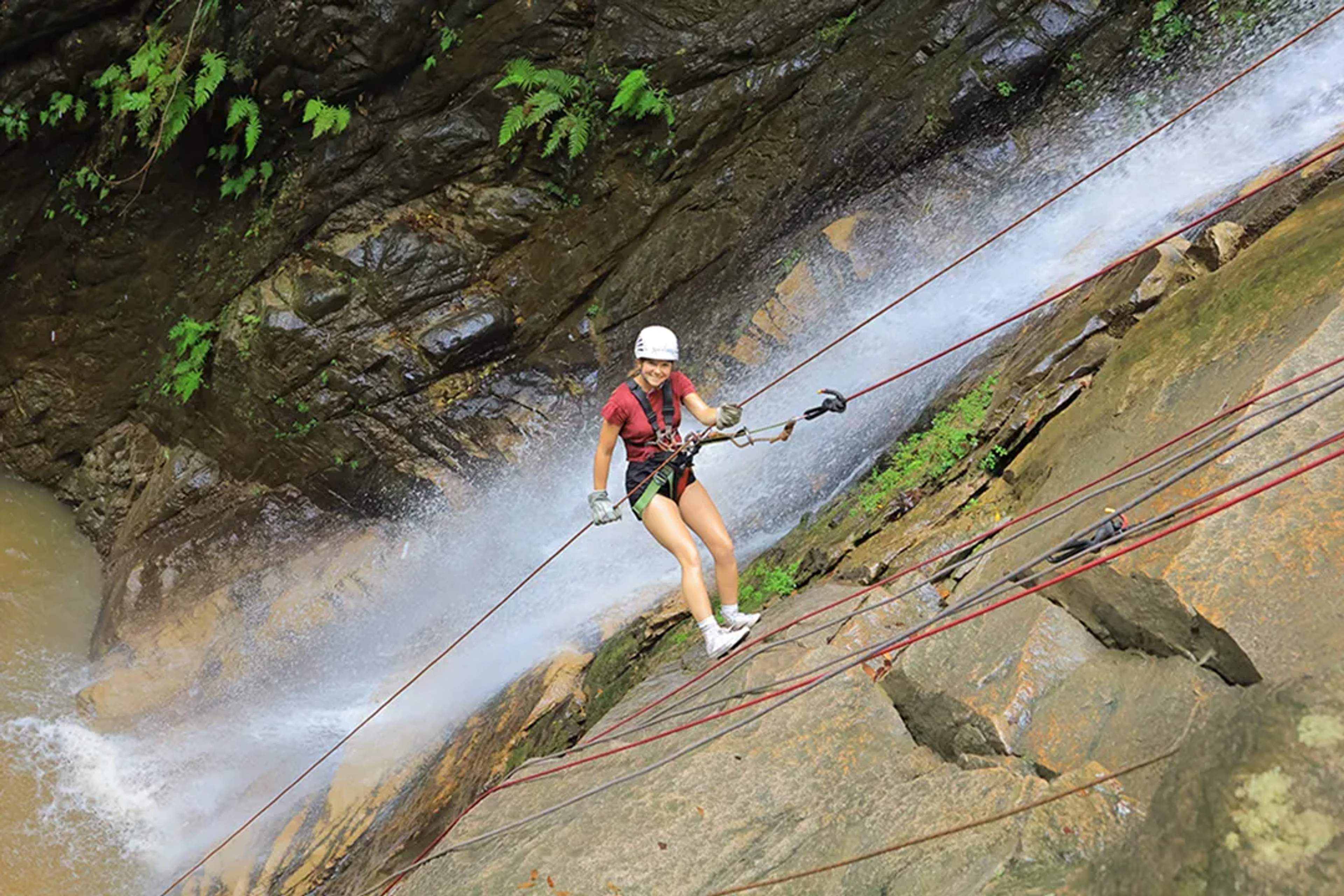 Traveler rappelling down a jungle waterfall near Puerto Vallarta, wearing safety gear during an outdoor adventure tour