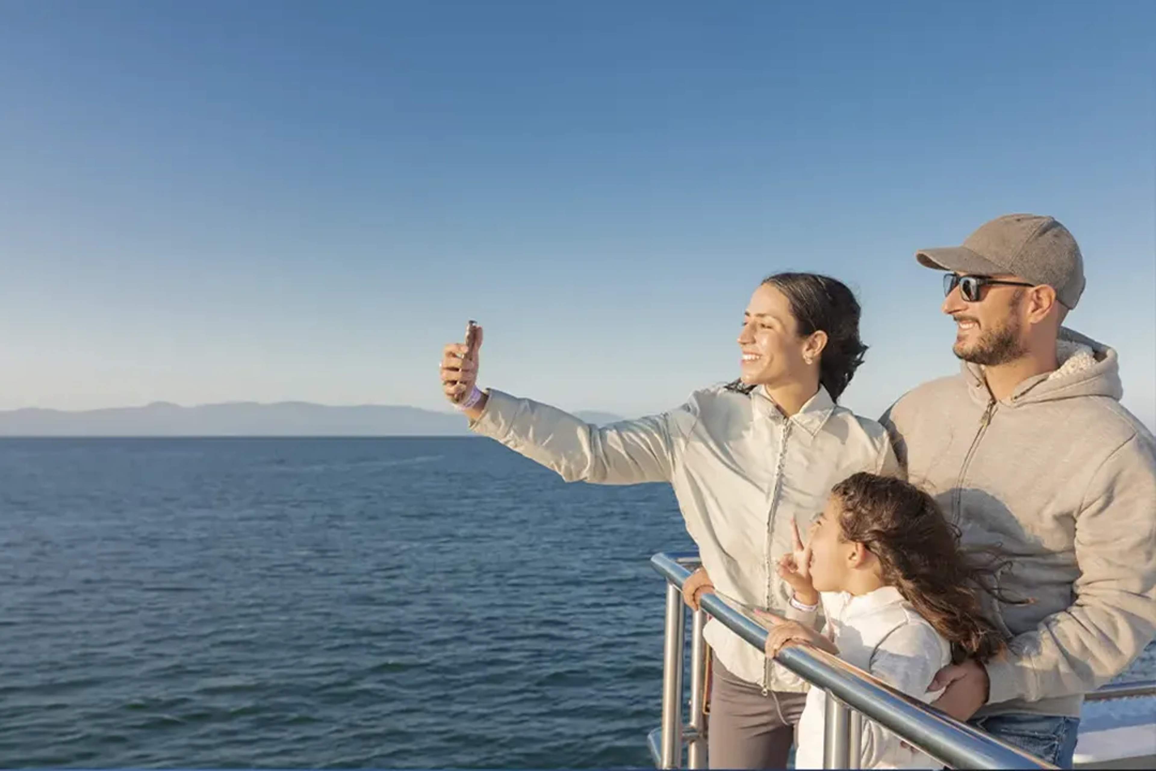 Una familia sonriente se toma una selfie en un barco durante un día soleado en Vallarta.